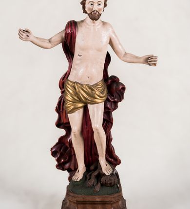 Zdjęcie nr 4: Pełnoplastyczna, całopostaciowa figura ukazuje Chrystusa Zmartwychwstałego stojącego na podłożu imitującym niewielki pagórek, osadzonym na profilowanej, prostopadłościennej podstawie o ściętych narożach. Zbawiciel na lekko ugiętych nogach ukazany został frontalnie. Obie ręce ma uniesione i odsunięte od tułowia. W lewej trzyma chorągiew na drzewcu z czerwonej tkaniny obszytej srebrną frędzlą i dekorowanej cekinami. Z kolei prawa jest uniesiona na wysokości klatki piersiowej. Jego sylwetka została opracowana sumarycznie z próbą uchwycenia muskulatury oraz zaznaczeniem partii żeber. Biodra Zbawiciela okrywa przewiązane, pozłocone perizonium. Chrystus ma owalną twarz o jasnej karnacji z charakterystycznie szeroko otwartymi oczami, wydatny nos i usta. Jego głowę otaczają krótkie brązowe włosy zaczesane do tyłu i zarost. Przez prawe ramię ma przerzucony, mocno sfałdowany, ciemnoczerwony płaszcz osłaniający tył sylwetki. Na dłoniach, stopach i w prawym boku widoczne są rany. Jezus lewą nogą depcze leżącego na podłożu szatana o groteskowej, brązowej sylwetce z ogonem, srebrzonymi, prostymi rogami, czerwonymi oczami oraz łapami zakończonymi czerwonymi pazurami. Na odwrocie widnieje napis: Odnowiono / 1960 St(Janisław) Rupik / Dzieło x(iędza) Roberta / Pioteckiego / 1615.
