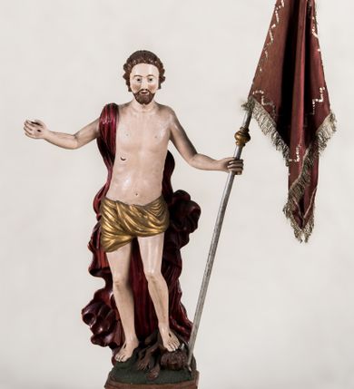 Zdjęcie nr 1: Pełnoplastyczna, całopostaciowa figura ukazuje Chrystusa Zmartwychwstałego stojącego na podłożu imitującym niewielki pagórek, osadzonym na profilowanej, prostopadłościennej podstawie o ściętych narożach. Zbawiciel na lekko ugiętych nogach ukazany został frontalnie. Obie ręce ma uniesione i odsunięte od tułowia. W lewej trzyma chorągiew na drzewcu z czerwonej tkaniny obszytej srebrną frędzlą i dekorowanej cekinami. Z kolei prawa jest uniesiona na wysokości klatki piersiowej. Jego sylwetka została opracowana sumarycznie z próbą uchwycenia muskulatury oraz zaznaczeniem partii żeber. Biodra Zbawiciela okrywa przewiązane, pozłocone perizonium. Chrystus ma owalną twarz o jasnej karnacji z charakterystycznie szeroko otwartymi oczami, wydatny nos i usta. Jego głowę otaczają krótkie brązowe włosy zaczesane do tyłu i zarost. Przez prawe ramię ma przerzucony, mocno sfałdowany, ciemnoczerwony płaszcz osłaniający tył sylwetki. Na dłoniach, stopach i w prawym boku widoczne są rany. Jezus lewą nogą depcze leżącego na podłożu szatana o groteskowej, brązowej sylwetce z ogonem, srebrzonymi, prostymi rogami, czerwonymi oczami oraz łapami zakończonymi czerwonymi pazurami. Na odwrocie widnieje napis: Odnowiono / 1960 St(Janisław) Rupik / Dzieło x(iędza) Roberta / Pioteckiego / 1615.
