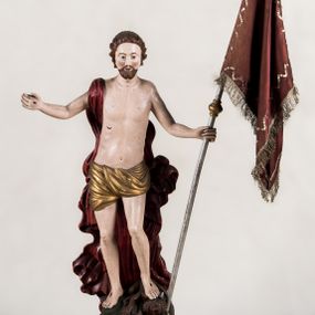 Zdjęcie nr 1: Pełnoplastyczna, całopostaciowa figura ukazuje Chrystusa Zmartwychwstałego stojącego na podłożu imitującym niewielki pagórek, osadzonym na profilowanej, prostopadłościennej podstawie o ściętych narożach. Zbawiciel na lekko ugiętych nogach ukazany został frontalnie. Obie ręce ma uniesione i odsunięte od tułowia. W lewej trzyma chorągiew na drzewcu z czerwonej tkaniny obszytej srebrną frędzlą i dekorowanej cekinami. Z kolei prawa jest uniesiona na wysokości klatki piersiowej. Jego sylwetka została opracowana sumarycznie z próbą uchwycenia muskulatury oraz zaznaczeniem partii żeber. Biodra Zbawiciela okrywa przewiązane, pozłocone perizonium. Chrystus ma owalną twarz o jasnej karnacji z charakterystycznie szeroko otwartymi oczami, wydatny nos i usta. Jego głowę otaczają krótkie brązowe włosy zaczesane do tyłu i zarost. Przez prawe ramię ma przerzucony, mocno sfałdowany, ciemnoczerwony płaszcz osłaniający tył sylwetki. Na dłoniach, stopach i w prawym boku widoczne są rany. Jezus lewą nogą depcze leżącego na podłożu szatana o groteskowej, brązowej sylwetce z ogonem, srebrzonymi, prostymi rogami, czerwonymi oczami oraz łapami zakończonymi czerwonymi pazurami. Na odwrocie widnieje napis: Odnowiono / 1960 St(Janisław) Rupik / Dzieło x(iędza) Roberta / Pioteckiego / 1615.
