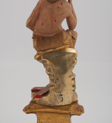 Zdjęcie nr 4: Rzeźba pełnoplastyczna, przyścienna, z tyłu ścięta, nieopracowana. Przedstawienie Chrystusa oczekującego na mękę, zwane Chrystus Frasobliwy lub Chrystus na zimnym głazie. Chrystus ukazany frontalnie, siedzi na niskiej skale, z rozsuniętymi kolanami, tułowiem przegiętym w prawą stronę i głową podpartą prawą ręką z łokciem wspartym na prawym kolanie Twarz okolona długimi, spływającymi na plecy włosami i zarostem. Na głowie korona cierniowa. Karnacja ciała z zaznaczonymi śladami męki. Na biodrach perizonium. U stóp Chrystusa leży krzyż. Rzeźba ustawiona na profilowanym postumencie.