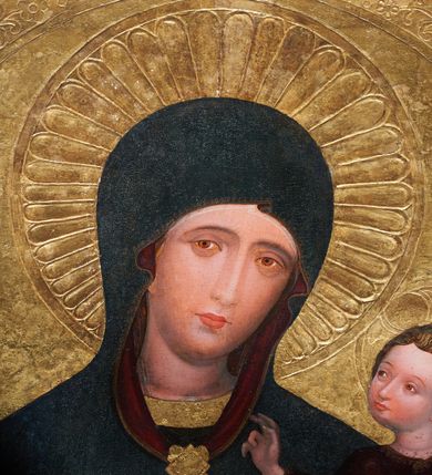 Zdjęcie nr 5: Obraz w kształcie stojącego prostokąta, z przedstawieniem Matki Boskiej z Dzieciątkiem w typie Hodegetrii Krakowskiej. Maria przedstawiona w półpostaci, z głową przechyloną na lewo. Lewą ręką obejmuje Dzieciątko, dłonią prawej ręki wskazuje na Syna. Twarz owalna o ciemnej karnacji z policzkami podkreślonymi różem, o regularnych łukach brwiowych, głęboko osadzonych oczach, długim wąskim nosie, drobnych czerwonych ustach. Dłonie wysmukłe, o długich palcach. Ubrana ciemnoniebieską suknię z wąskimi rękawami, ozdobioną pod szyją i końcach rękawów złotą bordiurą. Cała postać okryta maforium w takim samym kolorze co suknia, z czerwoną podszewką, ozdobionym cienką złotą lamówką i spiętym na piersiach rombową złotą broszą. Spod maforionu widoczny czepiec na głowie. Dzieciątko, ujęte w trzech czwartych, zwrócone w prawo, w kierunku Matki, Siedzi na jej lewym przedramieniu. Głowa kulista, z ciemnymi kędzierzawymi włosami ułożonymi w loki podkreślone złotymi kreskami ; twarz o ciemnej karnacji z zaróżowionymi policzkami. Prawą dłonią błogosławi, lewą podtrzymuje kodeks w czerwonej oprawie oparty na lewym kolanie. Ubrane w długą i szeroką ciemnoczerwoną sukienkę, ozdobioną drobnym wzorem patronowym malowanym złotem w proszku. Spod sukienki widać bose stopy.  Wokół głowy Marii nimb promienisty, wokół głowy Dzieciątka nimb krzyżowy. Tło (wtórne) złocone, w narożach z motywami uproszczonej wici roślinnej.
