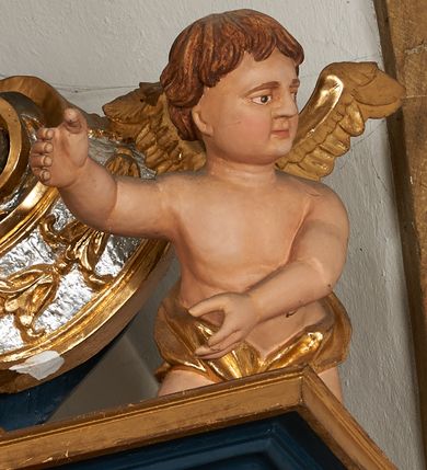 Zdjęcie nr 1: Para pełnoplastycznych rzeźb przedstawiających putta trzymające arma Christi. Aniołowie ukazani jako jasnowłosi chłopcy o owalnych twarzach z dużymi, brązowymi oczami i krótkimi, prostymi nosami. Postaci ubrane w luźno udrapowaną wokół bioder złotą tkaninę, odsłaniającą torsy i ramiona. Skrzydła złocone. Anioł z lewej trony przedstawiony w pozycji klęczącej z ciałem pochylonym do przodu. Oburącz podtrzymuje srebrzoną kolumnę o gruszkowatym trzonie. Anioł z prawej strony ołtarza klęczący z rękami wyciągniętymi do przodu, głowa zwrócona w lewo.