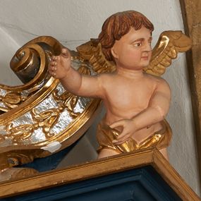 Zdjęcie nr 1: Para pełnoplastycznych rzeźb przedstawiających putta trzymające arma Christi. Aniołowie ukazani jako jasnowłosi chłopcy o owalnych twarzach z dużymi, brązowymi oczami i krótkimi, prostymi nosami. Postaci ubrane w luźno udrapowaną wokół bioder złotą tkaninę, odsłaniającą torsy i ramiona. Skrzydła złocone. Anioł z lewej trony przedstawiony w pozycji klęczącej z ciałem pochylonym do przodu. Oburącz podtrzymuje srebrzoną kolumnę o gruszkowatym trzonie. Anioł z prawej strony ołtarza klęczący z rękami wyciągniętymi do przodu, głowa zwrócona w lewo.