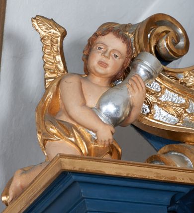 Zdjęcie nr 4: Para pełnoplastycznych rzeźb przedstawiających putta trzymające arma Christi. Aniołowie ukazani jako jasnowłosi chłopcy o owalnych twarzach z dużymi, brązowymi oczami i krótkimi, prostymi nosami. Postaci ubrane w luźno udrapowaną wokół bioder złotą tkaninę, odsłaniającą torsy i ramiona. Skrzydła złocone. Anioł z lewej trony przedstawiony w pozycji klęczącej z ciałem pochylonym do przodu. Oburącz podtrzymuje srebrzoną kolumnę o gruszkowatym trzonie. Anioł z prawej strony ołtarza klęczący z rękami wyciągniętymi do przodu, głowa zwrócona w lewo.