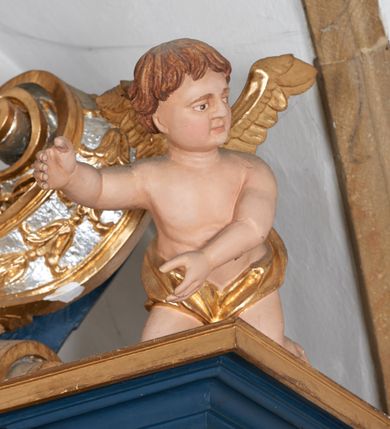 Zdjęcie nr 2: Para pełnoplastycznych rzeźb przedstawiających putta trzymające arma Christi. Aniołowie ukazani jako jasnowłosi chłopcy o owalnych twarzach z dużymi, brązowymi oczami i krótkimi, prostymi nosami. Postaci ubrane w luźno udrapowaną wokół bioder złotą tkaninę, odsłaniającą torsy i ramiona. Skrzydła złocone. Anioł z lewej trony przedstawiony w pozycji klęczącej z ciałem pochylonym do przodu. Oburącz podtrzymuje srebrzoną kolumnę o gruszkowatym trzonie. Anioł z prawej strony ołtarza klęczący z rękami wyciągniętymi do przodu, głowa zwrócona w lewo.