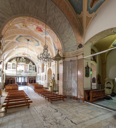 Zdjęcie nr 16: Po kilkukrotnych przekształceniach kościół składa się z prostokątnej, czteroprzęsłowej nawy głównej, dwóch, dwuprzęsłowych naw bocznych, przerobionych z dawnych kaplic i jednoprzęsłowego prezbiterium zamkniętego od wschodu apsydą. Na przedłużeniu apsydy otoczonej półkolistym aneksem wzniesiono czworoboczną, piętrową zakrystią. Od zachodu do nawy przylega wysunięta do przodu czworoboczna wieża o ściętych narożach z urządzoną w przyziemiu kruchtą. Wieża uzyskała trzy kondygnacje wyznaczone za pomocą profilowanych gzymsów. Środkowe piętro wieży połączono z bocznymi częściami fasady za pomocą wolut. Na dwóch pierwszych kondygnacjach ścięte naroża artykułowano za pomocą pilastrów o prostych głowicach. Pilastry drugiej kondygnacji ozdobiono krótkimi zwisami kampanul. Kondygnacja trzecia także została wzniesiona na rzucie czworoboku ale o wklęsłych narożach. Jej ściany flankują pary pilastrów o korynckich głowicach podtrzymujące imposty wspierające półkoliście wyłamane na osi belkowanie wspierające baniasty hełm z latarnią zwieńczony krzyżem z koroną. Pomiędzy impostami pod wyłamanym belkowaniem umieszczono tarcze zegarowe. Na trzeciej kondygnacji ponad belkowaniem od zachodu nadwieszono czworoboczny balkon z tralkową balustradą. Sześcioboczną sygnaturkę z latarnią zwieńczoną stożkowym hełmem z ustawioną na szczycie figurką Matki Boskiej Niepokalanie Poczętej zawieszono na siodłowym dachu kościoła w części wschodniej nawy głównej. Elewacje boczne kościoła rozczłonkowano za pomocą podziałów ramowych lub lizenowych. Wnętrze świątyni nakryto sklepieniem kolebkowym wspartym na gurtach, przechodzących na przyścienne pilastry podtrzymujące odcinki przerwanego belkowania. W ostanim zachodnim przęśle urządzono chór muzyczny wsparty na dwóch filarach z wypukłym na osi parapetem, artykułowanym za pomocą pilastrów i par arkadek. W prezbiterium ustawiono ołtarz główny oraz ambonę, a w nawach ołtarze boczne. 