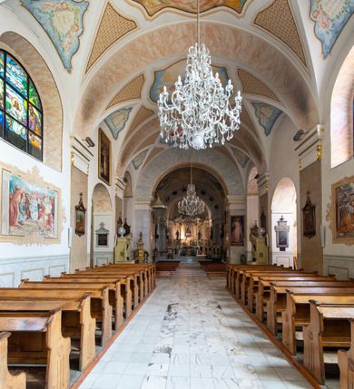 Zdjęcie nr 14: Po kilkukrotnych przekształceniach kościół składa się z prostokątnej, czteroprzęsłowej nawy głównej, dwóch, dwuprzęsłowych naw bocznych, przerobionych z dawnych kaplic i jednoprzęsłowego prezbiterium zamkniętego od wschodu apsydą. Na przedłużeniu apsydy otoczonej półkolistym aneksem wzniesiono czworoboczną, piętrową zakrystią. Od zachodu do nawy przylega wysunięta do przodu czworoboczna wieża o ściętych narożach z urządzoną w przyziemiu kruchtą. Wieża uzyskała trzy kondygnacje wyznaczone za pomocą profilowanych gzymsów. Środkowe piętro wieży połączono z bocznymi częściami fasady za pomocą wolut. Na dwóch pierwszych kondygnacjach ścięte naroża artykułowano za pomocą pilastrów o prostych głowicach. Pilastry drugiej kondygnacji ozdobiono krótkimi zwisami kampanul. Kondygnacja trzecia także została wzniesiona na rzucie czworoboku ale o wklęsłych narożach. Jej ściany flankują pary pilastrów o korynckich głowicach podtrzymujące imposty wspierające półkoliście wyłamane na osi belkowanie wspierające baniasty hełm z latarnią zwieńczony krzyżem z koroną. Pomiędzy impostami pod wyłamanym belkowaniem umieszczono tarcze zegarowe. Na trzeciej kondygnacji ponad belkowaniem od zachodu nadwieszono czworoboczny balkon z tralkową balustradą. Sześcioboczną sygnaturkę z latarnią zwieńczoną stożkowym hełmem z ustawioną na szczycie figurką Matki Boskiej Niepokalanie Poczętej zawieszono na siodłowym dachu kościoła w części wschodniej nawy głównej. Elewacje boczne kościoła rozczłonkowano za pomocą podziałów ramowych lub lizenowych. Wnętrze świątyni nakryto sklepieniem kolebkowym wspartym na gurtach, przechodzących na przyścienne pilastry podtrzymujące odcinki przerwanego belkowania. W ostanim zachodnim przęśle urządzono chór muzyczny wsparty na dwóch filarach z wypukłym na osi parapetem, artykułowanym za pomocą pilastrów i par arkadek. W prezbiterium ustawiono ołtarz główny oraz ambonę, a w nawach ołtarze boczne. 