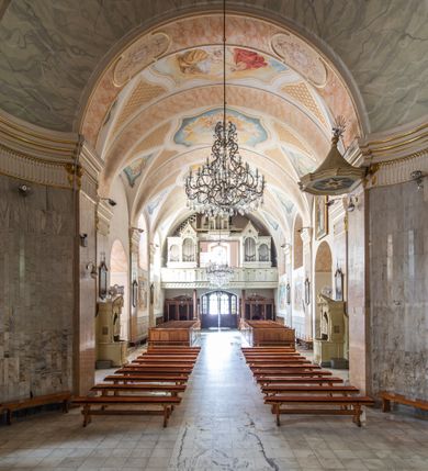 Zdjęcie nr 19: Po kilkukrotnych przekształceniach kościół składa się z prostokątnej, czteroprzęsłowej nawy głównej, dwóch, dwuprzęsłowych naw bocznych, przerobionych z dawnych kaplic i jednoprzęsłowego prezbiterium zamkniętego od wschodu apsydą. Na przedłużeniu apsydy otoczonej półkolistym aneksem wzniesiono czworoboczną, piętrową zakrystią. Od zachodu do nawy przylega wysunięta do przodu czworoboczna wieża o ściętych narożach z urządzoną w przyziemiu kruchtą. Wieża uzyskała trzy kondygnacje wyznaczone za pomocą profilowanych gzymsów. Środkowe piętro wieży połączono z bocznymi częściami fasady za pomocą wolut. Na dwóch pierwszych kondygnacjach ścięte naroża artykułowano za pomocą pilastrów o prostych głowicach. Pilastry drugiej kondygnacji ozdobiono krótkimi zwisami kampanul. Kondygnacja trzecia także została wzniesiona na rzucie czworoboku ale o wklęsłych narożach. Jej ściany flankują pary pilastrów o korynckich głowicach podtrzymujące imposty wspierające półkoliście wyłamane na osi belkowanie wspierające baniasty hełm z latarnią zwieńczony krzyżem z koroną. Pomiędzy impostami pod wyłamanym belkowaniem umieszczono tarcze zegarowe. Na trzeciej kondygnacji ponad belkowaniem od zachodu nadwieszono czworoboczny balkon z tralkową balustradą. Sześcioboczną sygnaturkę z latarnią zwieńczoną stożkowym hełmem z ustawioną na szczycie figurką Matki Boskiej Niepokalanie Poczętej zawieszono na siodłowym dachu kościoła w części wschodniej nawy głównej. Elewacje boczne kościoła rozczłonkowano za pomocą podziałów ramowych lub lizenowych. Wnętrze świątyni nakryto sklepieniem kolebkowym wspartym na gurtach, przechodzących na przyścienne pilastry podtrzymujące odcinki przerwanego belkowania. W ostanim zachodnim przęśle urządzono chór muzyczny wsparty na dwóch filarach z wypukłym na osi parapetem, artykułowanym za pomocą pilastrów i par arkadek. W prezbiterium ustawiono ołtarz główny oraz ambonę, a w nawach ołtarze boczne. 