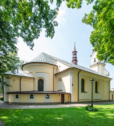 Zdjęcie nr 2: Po kilkukrotnych przekształceniach kościół składa się z prostokątnej, czteroprzęsłowej nawy głównej, dwóch, dwuprzęsłowych naw bocznych, przerobionych z dawnych kaplic i jednoprzęsłowego prezbiterium zamkniętego od wschodu apsydą. Na przedłużeniu apsydy otoczonej półkolistym aneksem wzniesiono czworoboczną, piętrową zakrystią. Od zachodu do nawy przylega wysunięta do przodu czworoboczna wieża o ściętych narożach z urządzoną w przyziemiu kruchtą. Wieża uzyskała trzy kondygnacje wyznaczone za pomocą profilowanych gzymsów. Środkowe piętro wieży połączono z bocznymi częściami fasady za pomocą wolut. Na dwóch pierwszych kondygnacjach ścięte naroża artykułowano za pomocą pilastrów o prostych głowicach. Pilastry drugiej kondygnacji ozdobiono krótkimi zwisami kampanul. Kondygnacja trzecia także została wzniesiona na rzucie czworoboku ale o wklęsłych narożach. Jej ściany flankują pary pilastrów o korynckich głowicach podtrzymujące imposty wspierające półkoliście wyłamane na osi belkowanie wspierające baniasty hełm z latarnią zwieńczony krzyżem z koroną. Pomiędzy impostami pod wyłamanym belkowaniem umieszczono tarcze zegarowe. Na trzeciej kondygnacji ponad belkowaniem od zachodu nadwieszono czworoboczny balkon z tralkową balustradą. Sześcioboczną sygnaturkę z latarnią zwieńczoną stożkowym hełmem z ustawioną na szczycie figurką Matki Boskiej Niepokalanie Poczętej zawieszono na siodłowym dachu kościoła w części wschodniej nawy głównej. Elewacje boczne kościoła rozczłonkowano za pomocą podziałów ramowych lub lizenowych. Wnętrze świątyni nakryto sklepieniem kolebkowym wspartym na gurtach, przechodzących na przyścienne pilastry podtrzymujące odcinki przerwanego belkowania. W ostanim zachodnim przęśle urządzono chór muzyczny wsparty na dwóch filarach z wypukłym na osi parapetem, artykułowanym za pomocą pilastrów i par arkadek. W prezbiterium ustawiono ołtarz główny oraz ambonę, a w nawach ołtarze boczne. 