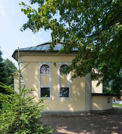 Zdjęcie nr 26: Po kilkukrotnych przekształceniach kościół składa się z prostokątnej, czteroprzęsłowej nawy głównej, dwóch, dwuprzęsłowych naw bocznych, przerobionych z dawnych kaplic i jednoprzęsłowego prezbiterium zamkniętego od wschodu apsydą. Na przedłużeniu apsydy otoczonej półkolistym aneksem wzniesiono czworoboczną, piętrową zakrystią. Od zachodu do nawy przylega wysunięta do przodu czworoboczna wieża o ściętych narożach z urządzoną w przyziemiu kruchtą. Wieża uzyskała trzy kondygnacje wyznaczone za pomocą profilowanych gzymsów. Środkowe piętro wieży połączono z bocznymi częściami fasady za pomocą wolut. Na dwóch pierwszych kondygnacjach ścięte naroża artykułowano za pomocą pilastrów o prostych głowicach. Pilastry drugiej kondygnacji ozdobiono krótkimi zwisami kampanul. Kondygnacja trzecia także została wzniesiona na rzucie czworoboku ale o wklęsłych narożach. Jej ściany flankują pary pilastrów o korynckich głowicach podtrzymujące imposty wspierające półkoliście wyłamane na osi belkowanie wspierające baniasty hełm z latarnią zwieńczony krzyżem z koroną. Pomiędzy impostami pod wyłamanym belkowaniem umieszczono tarcze zegarowe. Na trzeciej kondygnacji ponad belkowaniem od zachodu nadwieszono czworoboczny balkon z tralkową balustradą. Sześcioboczną sygnaturkę z latarnią zwieńczoną stożkowym hełmem z ustawioną na szczycie figurką Matki Boskiej Niepokalanie Poczętej zawieszono na siodłowym dachu kościoła w części wschodniej nawy głównej. Elewacje boczne kościoła rozczłonkowano za pomocą podziałów ramowych lub lizenowych. Wnętrze świątyni nakryto sklepieniem kolebkowym wspartym na gurtach, przechodzących na przyścienne pilastry podtrzymujące odcinki przerwanego belkowania. W ostanim zachodnim przęśle urządzono chór muzyczny wsparty na dwóch filarach z wypukłym na osi parapetem, artykułowanym za pomocą pilastrów i par arkadek. W prezbiterium ustawiono ołtarz główny oraz ambonę, a w nawach ołtarze boczne. 