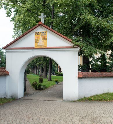 Zdjęcie nr 30: Po kilkukrotnych przekształceniach kościół składa się z prostokątnej, czteroprzęsłowej nawy głównej, dwóch, dwuprzęsłowych naw bocznych, przerobionych z dawnych kaplic i jednoprzęsłowego prezbiterium zamkniętego od wschodu apsydą. Na przedłużeniu apsydy otoczonej półkolistym aneksem wzniesiono czworoboczną, piętrową zakrystią. Od zachodu do nawy przylega wysunięta do przodu czworoboczna wieża o ściętych narożach z urządzoną w przyziemiu kruchtą. Wieża uzyskała trzy kondygnacje wyznaczone za pomocą profilowanych gzymsów. Środkowe piętro wieży połączono z bocznymi częściami fasady za pomocą wolut. Na dwóch pierwszych kondygnacjach ścięte naroża artykułowano za pomocą pilastrów o prostych głowicach. Pilastry drugiej kondygnacji ozdobiono krótkimi zwisami kampanul. Kondygnacja trzecia także została wzniesiona na rzucie czworoboku ale o wklęsłych narożach. Jej ściany flankują pary pilastrów o korynckich głowicach podtrzymujące imposty wspierające półkoliście wyłamane na osi belkowanie wspierające baniasty hełm z latarnią zwieńczony krzyżem z koroną. Pomiędzy impostami pod wyłamanym belkowaniem umieszczono tarcze zegarowe. Na trzeciej kondygnacji ponad belkowaniem od zachodu nadwieszono czworoboczny balkon z tralkową balustradą. Sześcioboczną sygnaturkę z latarnią zwieńczoną stożkowym hełmem z ustawioną na szczycie figurką Matki Boskiej Niepokalanie Poczętej zawieszono na siodłowym dachu kościoła w części wschodniej nawy głównej. Elewacje boczne kościoła rozczłonkowano za pomocą podziałów ramowych lub lizenowych. Wnętrze świątyni nakryto sklepieniem kolebkowym wspartym na gurtach, przechodzących na przyścienne pilastry podtrzymujące odcinki przerwanego belkowania. W ostanim zachodnim przęśle urządzono chór muzyczny wsparty na dwóch filarach z wypukłym na osi parapetem, artykułowanym za pomocą pilastrów i par arkadek. W prezbiterium ustawiono ołtarz główny oraz ambonę, a w nawach ołtarze boczne. 
