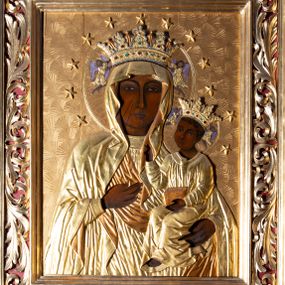 Zdjęcie nr 1: Obraz uzyskał kształt stojącego prostokąta ujętego w dekoracyjną ramę ozdobioną złoconym ażurowym motywem wici roślinnej na czerwonym tle. Obie postacie w całości przykrywa drewniana, złocona sukienka wotywna z koronami, odsłaniająca tylko partie twarzy i rąk oraz stopę Dzieciątka. Madonna została ukazana frontalnie w półpostaci. Prawą ręką wskazuje na trzymane na lewym ramieniu Dzieciątko Jezus. Jej podłużną twarz o ciemnej karnacji charakteryzuje wydatny, prosty nos, migdałowe oczy, mięsiste usta oraz dwa równoległe cięcia widoczne na prawym policzku. Na głowie ma maforion odsłaniający fragment sukni lamowanej pod szyją galonem. Maria ma na głowie koronę o wysokich sterczynach dekorowaną imitacją kameryzacji. Dzieciątko zostało ujęte w trzech czwartych w lewo. Prawą rękę wznosi w geście błogosławieństwa, w lewej natomiast trzyma gruby kodeks Ewangelii. Mały Jezus ma owalną twarz o ciemnej karnacji. Widoczny jest wydatny nos i usta oraz szeroko otwarte oczy. Ma na sobie tunikę lamowaną pod szyją galonem. Głowę Chrystusa wieńczy korona, kształtem i dekoracją zbliżona do korony Madonny. Korony obu postaci podtrzymuje para aniołów o jasnofioletowych skrzydłach. Wokół głowy Marii i Jezusa umieszczono dwanaście aplikowanych gwiazd na złotym, grzebykowanym tle.