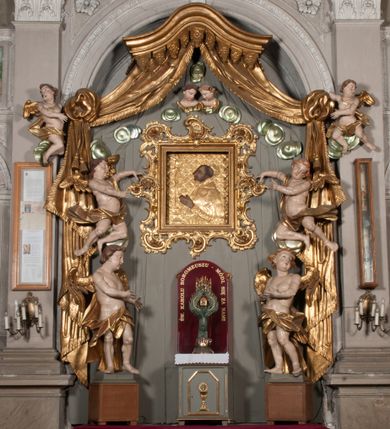 Zdjęcie nr 1: Nastawa niearchitektoniczna w formie paludamentu. Mensa kamienna, oparta na dwóch kamiennych pilastrach o kanelowanych trzonach, ustawionych na cokolikach. Na mensie  tabernakulum w formie drewnianej skrzynki na czterech nóżkach, zakończone gzymsem, o drzwiczkach w kształcie stojącego prostokąta o ściętych górnych narożach, ujęte profilowaną ramą z przedstawieniem kielicha z hostią w glorii. Na nim tron wystawienia na relikwiarz. Tabernakulum flankują dwie figury aniołów ustawione na cokołach. 
Paludament podwiązany po bokach sznurem z chwostami, podtrzymywany przez putta, lamowany frędzlą, zwieńczony baldachimem utworzonym z fragmentu wklęsło-wypukłego gzymsu z lambrekinem. W polu wnęka w kształcie stojącego prostokąta ujęta profilowaną ramą i rocaille&#039;m, z obrazem św. Karola Boromeusza. Nad obrazem rzeźbione obłoki i dwie uskrzydlone główki anielskie, po bokach nadlatujące dwa putta. Paludament polichromowany wewnątrz w kolorze szaro-brązowym, zewnątrz złocony.