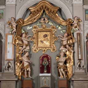 Zdjęcie nr 1: Nastawa niearchitektoniczna w formie paludamentu. Mensa kamienna, oparta na dwóch kamiennych pilastrach o kanelowanych trzonach, ustawionych na cokolikach. Na mensie  tabernakulum w formie drewnianej skrzynki na czterech nóżkach, zakończone gzymsem, o drzwiczkach w kształcie stojącego prostokąta o ściętych górnych narożach, ujęte profilowaną ramą z przedstawieniem kielicha z hostią w glorii. Na nim tron wystawienia na relikwiarz. Tabernakulum flankują dwie figury aniołów ustawione na cokołach. 
Paludament podwiązany po bokach sznurem z chwostami, podtrzymywany przez putta, lamowany frędzlą, zwieńczony baldachimem utworzonym z fragmentu wklęsło-wypukłego gzymsu z lambrekinem. W polu wnęka w kształcie stojącego prostokąta ujęta profilowaną ramą i rocaille'm, z obrazem św. Karola Boromeusza. Nad obrazem rzeźbione obłoki i dwie uskrzydlone główki anielskie, po bokach nadlatujące dwa putta. Paludament polichromowany wewnątrz w kolorze szaro-brązowym, zewnątrz złocony.