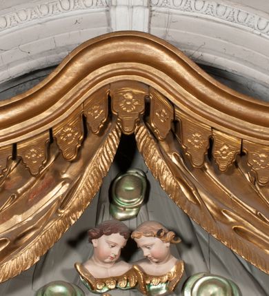 Zdjęcie nr 9: Nastawa niearchitektoniczna w formie paludamentu. Mensa kamienna, oparta na dwóch kamiennych pilastrach o kanelowanych trzonach, ustawionych na cokolikach. Na mensie  tabernakulum w formie drewnianej skrzynki na czterech nóżkach, zakończone gzymsem, o drzwiczkach w kształcie stojącego prostokąta o ściętych górnych narożach, ujęte profilowaną ramą z przedstawieniem kielicha z hostią w glorii. Na nim tron wystawienia na relikwiarz. Tabernakulum flankują dwie figury aniołów ustawione na cokołach. 
Paludament podwiązany po bokach sznurem z chwostami, podtrzymywany przez putta, lamowany frędzlą, zwieńczony baldachimem utworzonym z fragmentu wklęsło-wypukłego gzymsu z lambrekinem. W polu wnęka w kształcie stojącego prostokąta ujęta profilowaną ramą i rocaille&#039;m, z obrazem św. Karola Boromeusza. Nad obrazem rzeźbione obłoki i dwie uskrzydlone główki anielskie, po bokach nadlatujące dwa putta. Paludament polichromowany wewnątrz w kolorze szaro-brązowym, zewnątrz złocony.