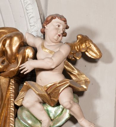 Zdjęcie nr 31: Nastawa niearchitektoniczna w formie paludamentu. Mensa kamienna, oparta na dwóch kamiennych pilastrach o kanelowanych trzonach, ustawionych na cokolikach. Na mensie  tabernakulum w formie drewnianej skrzynki na czterech nóżkach, zakończone gzymsem, o drzwiczkach w kształcie stojącego prostokąta o ściętych górnych narożach, ujęte profilowaną ramą z przedstawieniem kielicha z hostią w glorii. Na nim tron wystawienia na relikwiarz. Tabernakulum flankują dwie figury aniołów ustawione na cokołach. 
Paludament podwiązany po bokach sznurem z chwostami, podtrzymywany przez putta, lamowany frędzlą, zwieńczony baldachimem utworzonym z fragmentu wklęsło-wypukłego gzymsu z lambrekinem. W polu wnęka w kształcie stojącego prostokąta ujęta profilowaną ramą i rocaille'm, z obrazem św. Karola Boromeusza. Nad obrazem rzeźbione obłoki i dwie uskrzydlone główki anielskie, po bokach nadlatujące dwa putta. Paludament polichromowany wewnątrz w kolorze szaro-brązowym, zewnątrz złocony.