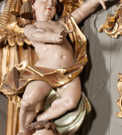 Zdjęcie nr 26: Nastawa niearchitektoniczna w formie paludamentu. Mensa kamienna, oparta na dwóch kamiennych pilastrach o kanelowanych trzonach, ustawionych na cokolikach. Na mensie  tabernakulum w formie drewnianej skrzynki na czterech nóżkach, zakończone gzymsem, o drzwiczkach w kształcie stojącego prostokąta o ściętych górnych narożach, ujęte profilowaną ramą z przedstawieniem kielicha z hostią w glorii. Na nim tron wystawienia na relikwiarz. Tabernakulum flankują dwie figury aniołów ustawione na cokołach. 
Paludament podwiązany po bokach sznurem z chwostami, podtrzymywany przez putta, lamowany frędzlą, zwieńczony baldachimem utworzonym z fragmentu wklęsło-wypukłego gzymsu z lambrekinem. W polu wnęka w kształcie stojącego prostokąta ujęta profilowaną ramą i rocaille'm, z obrazem św. Karola Boromeusza. Nad obrazem rzeźbione obłoki i dwie uskrzydlone główki anielskie, po bokach nadlatujące dwa putta. Paludament polichromowany wewnątrz w kolorze szaro-brązowym, zewnątrz złocony.