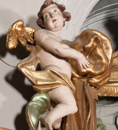 Zdjęcie nr 34: Nastawa niearchitektoniczna w formie paludamentu. Mensa kamienna, oparta na dwóch kamiennych pilastrach o kanelowanych trzonach, ustawionych na cokolikach. Na mensie  tabernakulum w formie drewnianej skrzynki na czterech nóżkach, zakończone gzymsem, o drzwiczkach w kształcie stojącego prostokąta o ściętych górnych narożach, ujęte profilowaną ramą z przedstawieniem kielicha z hostią w glorii. Na nim tron wystawienia na relikwiarz. Tabernakulum flankują dwie figury aniołów ustawione na cokołach. 
Paludament podwiązany po bokach sznurem z chwostami, podtrzymywany przez putta, lamowany frędzlą, zwieńczony baldachimem utworzonym z fragmentu wklęsło-wypukłego gzymsu z lambrekinem. W polu wnęka w kształcie stojącego prostokąta ujęta profilowaną ramą i rocaille'm, z obrazem św. Karola Boromeusza. Nad obrazem rzeźbione obłoki i dwie uskrzydlone główki anielskie, po bokach nadlatujące dwa putta. Paludament polichromowany wewnątrz w kolorze szaro-brązowym, zewnątrz złocony.