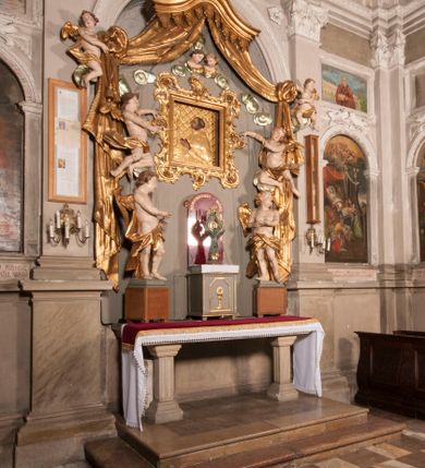 Zdjęcie nr 35: Nastawa niearchitektoniczna w formie paludamentu. Mensa kamienna, oparta na dwóch kamiennych pilastrach o kanelowanych trzonach, ustawionych na cokolikach. Na mensie  tabernakulum w formie drewnianej skrzynki na czterech nóżkach, zakończone gzymsem, o drzwiczkach w kształcie stojącego prostokąta o ściętych górnych narożach, ujęte profilowaną ramą z przedstawieniem kielicha z hostią w glorii. Na nim tron wystawienia na relikwiarz. Tabernakulum flankują dwie figury aniołów ustawione na cokołach. 
Paludament podwiązany po bokach sznurem z chwostami, podtrzymywany przez putta, lamowany frędzlą, zwieńczony baldachimem utworzonym z fragmentu wklęsło-wypukłego gzymsu z lambrekinem. W polu wnęka w kształcie stojącego prostokąta ujęta profilowaną ramą i rocaille'm, z obrazem św. Karola Boromeusza. Nad obrazem rzeźbione obłoki i dwie uskrzydlone główki anielskie, po bokach nadlatujące dwa putta. Paludament polichromowany wewnątrz w kolorze szaro-brązowym, zewnątrz złocony.