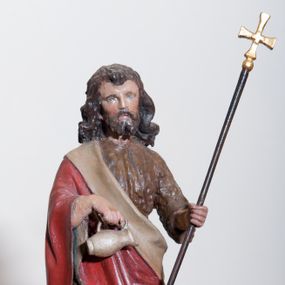 Zdjęcie nr 1: Rzeźba ustawiona na pokrywie chrzcielnicy, pełna, przedstawiająca św. Jana Chrzciciela. Święty ukazany w całej postaci, w delikatnym kontrapoście. W prawej dłoni trzyma dzbanuszek do polania wodą, a w lewej równoramienny krzyż na długim drzewcu. U jego prawej nogi leży biały baranek. Twarz podłużna o sumarycznie oddanych detalach, małe oczy i usta, krótki nos. Włosy bujne, ciemnobrązowe, opadają na plecy i ramiona, broda krótka rozdzielona na końcu w dwa pukle. Święty ubrany jest w suknię wykonaną z wielbłądziej skóry, sięgającą połowy łydek oraz czerwony płaszcz z jasnobeżową podszewką założony na prawe ramię i spływający pod lewą ręką. Draperia szat spokojna, niewielka. Polichromia w odsłoniętych partiach ciała naturalistyczna. 