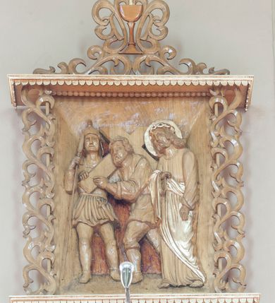 Zdjęcie nr 1: Stacje drogi krzyżowej w formie płaskorzeźbionych scen ujętych rozbudowanym obramieniem. Przedstawienia ograniczają się do najważniejszych osób, ukazanych w całej postaci i bliskim planie, na jednolitym, nieco ciemniejszym od reszty tle. Sposób ukazania postaci nosi cechy sztuki ludowej, ich pozy są sztywne, twarze zwrócone do widza, szaty marszczą się drobnymi fałdami. Postacie, ich ubrania oraz elementy scen zachowują naturalny kolor drewna, jedynie ubrania i nimb Chrystusa podkreślono złoceniem. Sceny zakomponowano w obramienie przypominające kapliczkę – na podstawie i pod daszkiem dekorowanymi lambrekinem, ujęte po bokach ażurową wicią roślinną. Poniżej podstawy numer sceny, a powyżej kielich z zatkniętym krzyżem łacińskim otacza i łączy w całość podobna wić. Lambrekin, krzyż oraz cyfry rzymskie złocone, reszta w kolorze naturalnego drewna. 