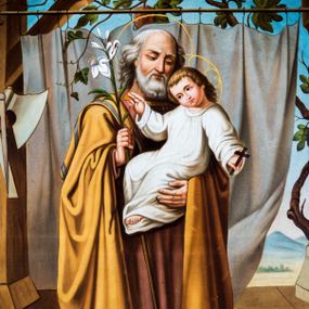 Zdjęcie nr 1: Obraz uzyskał formę stojącego prostokąta z całopostaciowym przedstawieniem św. Józefa z Dzieciątkiem. Józef zwrócony jest nieznacznie w trzech czwartych w lewo, z pochyloną głową. Święty lewą ręką podtrzymuje Dzieciątko, w prawej natomiast trzyma laskę zakończoną gałązką lilii. Twarz ma owalną, o starczych rysach, wysokim czole i migdałowatych oczach skierowanych w dół, długim nosie i pełnych ustach, okoloną siwą brodą oraz siwymi włosami sięgającymi ramion. Ubrany jest w długą ciemnoróżową tunikę oraz obficie drapowany, ciemnożółty płaszcz z zielonym pasem wzdłuż krawędzi zarzucony na ramiona. Wokół jego głowy widoczna jest złota aureola. Dzieciątko zwrócone zostało w trzech czwartych w prawo. Jezus z pochyloną głową i skrzyżowanymi stopami, prawą rękę unosi w geście błogosławieństwa, a w opuszczonej lewej dłoni trzyma krzyżyk. Zbawiciel ma okragłą twarz o dużych oczach, małym nosie i ustach, otoczoną jasnymi, krótkimi włosami. Jego głowę okala stylizowany nimb krzyżowy. Ubrany jest w białą obfitą tunikę. Postacie zostały ukazane w bliżej nieokreślonym wnętrzu otwierającym się na pejzaż zasadniczo przesłonięty kotarą zawieszoną na drążku, po którym pnie się winna latorośl. Po lewej stronie obrazu widoczne są zawieszone na filarze narzędzia ciesielskie (siekiera, kątownica, cyrkiel), a w prawym dolnym rogu wazon z różami.