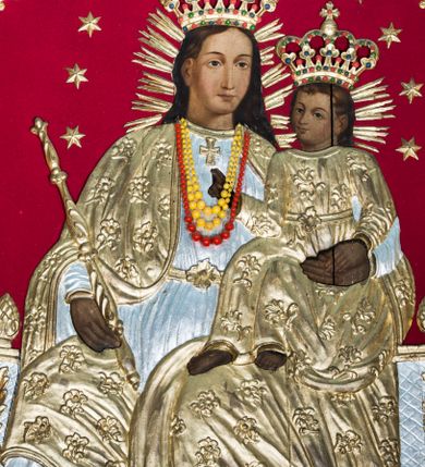 Zdjęcie nr 1: Obraz uzyskał formę stojącego prostokąta zamkniętego łukiem półkolistym nadwieszonym z uskokiem. Postacie na obrazie w partii ciała przykryte zostały drewnianymi sukienkami wotywnymi. Na głowach otoczonych promieniami mają wotywne korony zamknięte dekorowane malowaną kameryzacją. Wokół ich głów widać złocone gwiazdki umieszczone na czerwonym aksamicie okrywającym tło obrazu. Drewniana sukienka pokrywa także partie tronu, na którym siedzi Madonna. W centrum kompozycji ukazano tronującą Matkę Boską z Dzieciątkiem. Frontalnie siedząca na tronie Maria została ukazana do kolan z głową zwrócona w trzech czwartych w lewo. Lewą ręką podtrzymuje na kolanach Dzieciątko, w prawej zaś berło. Madonna ma pociągłą twarz o jasnej karnacji i łagodnych rysach, migdałowe oczy, prosty nos i pełne usta. Jej głowę okalają długie brązowe włosy spływające na plecy. Maria ubrana jest w srebrzoną suknię przepasaną w talii z krzyżem u szyi oraz złocony płaszcz zarzucony na ramiona i opadający na kolana dekorowany kwiatowym wzorem. Siedzące na kolanach matki Dzieciątko skierowane jest w trzech czwartych w prawo. Prawą rękę unosi w geście błogosławieństwa, lewą kładzie na dłoni Marii. Mały Jezus ma okrągła twarz o jasnej karnacji, duże oczy, mały nos i pełne usta. Jego głowę okalają krótkie, brązowe włosy odsłaniające lewe ucho. Dzieciątko ubrane jest w tunikę o kwiecistym wzorze przepasaną w talii. 