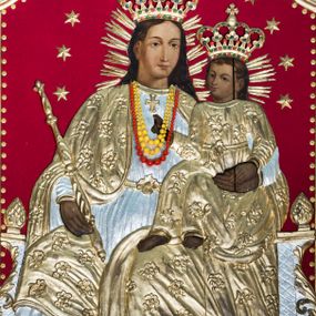 Zdjęcie nr 1: Obraz uzyskał formę stojącego prostokąta zamkniętego łukiem półkolistym nadwieszonym z uskokiem. Postacie na obrazie w partii ciała przykryte zostały drewnianymi sukienkami wotywnymi. Na głowach otoczonych promieniami mają wotywne korony zamknięte dekorowane malowaną kameryzacją. Wokół ich głów widać złocone gwiazdki umieszczone na czerwonym aksamicie okrywającym tło obrazu. Drewniana sukienka pokrywa także partie tronu, na którym siedzi Madonna. W centrum kompozycji ukazano tronującą Matkę Boską z Dzieciątkiem. Frontalnie siedząca na tronie Maria została ukazana do kolan z głową zwrócona w trzech czwartych w lewo. Lewą ręką podtrzymuje na kolanach Dzieciątko, w prawej zaś berło. Madonna ma pociągłą twarz o jasnej karnacji i łagodnych rysach, migdałowe oczy, prosty nos i pełne usta. Jej głowę okalają długie brązowe włosy spływające na plecy. Maria ubrana jest w srebrzoną suknię przepasaną w talii z krzyżem u szyi oraz złocony płaszcz zarzucony na ramiona i opadający na kolana dekorowany kwiatowym wzorem. Siedzące na kolanach matki Dzieciątko skierowane jest w trzech czwartych w prawo. Prawą rękę unosi w geście błogosławieństwa, lewą kładzie na dłoni Marii. Mały Jezus ma okrągła twarz o jasnej karnacji, duże oczy, mały nos i pełne usta. Jego głowę okalają krótkie, brązowe włosy odsłaniające lewe ucho. Dzieciątko ubrane jest w tunikę o kwiecistym wzorze przepasaną w talii. 