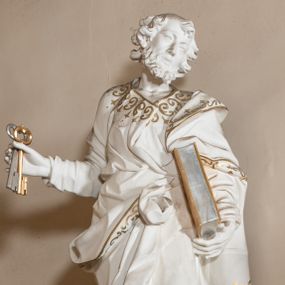 Zdjęcie nr 1: Rzeźba drążona z tyłu, stoi na prostokątnej podstawie ustawionej na wolutowej konsoli przyściennej. Postać apostoła jest ujęta frontalnie w kontrapoście z głową skierowaną i pochyloną w lewo. W prawej ręce odsuniętej od siebie apostoł trzyma klucze, a lewą podtrzymuje opartą o tors księgę. Piotr ma pociągłą, wychudzoną twarzą o migdałowatych oczach, małym nosie i pełnych ustach. Otacza ja krótka, kręcona broda i mocno kręcone włosy z łysiną na głowie. Postać ubrana jest w długą, przylegającą do ciała tunikę, przewiązaną w pasie oraz płaszcz zarzucony na lewe ramię, opadający na plecy, z fragmentem tkaniny przerzuconym przez prawe biodro, podwiązanym na wysokości pasa. Rzeźba została w całości polichromowana na biało ze złoconymi lamówkami szat i wzorem dekoracyjnym poprowadzonym wzdłuż krawędzi. Klucze i księga zostały wysrebrzone i wyzłocone.