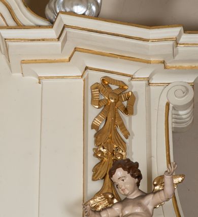 Zdjęcie nr 14: Dwukondygnacyjny, jednoosiowy ołtarz ze zwieńczeniem uzyskał strukturę architektoniczną. Stipes ołtarzowy wykonano w formie granitowego prostopadłościanu z mensą. Na mensie na osi ołtarza ustawiono tabernakulum z tronem wystawienia. Tabernakulum otrzymało kształt drewnianej skrzynki obitej blachą z drzwiczkami w formie stojącego prostokąta, z sześcioma kwaterami przedstawiającymi sceny z Pisma Świętego. Całość zamknięto silnie wysuniętym gzymsem wypukłym od frontu. Tron wystawienia utworzono w formie baldachimu ozdobionego lambrekinem z chwostami. Ujmują go spływy wolutowe z podwieszoną tkaniną, dekorowane liśćmi akantu. W przestrzeni zaplecka tronu umieszczono w promienistej glorii medalion z chrystogramem "IHS". Nastawa została ustawiona na wysokim cokole, zwieńczonym profilowanym gzymsem z wyodrębnionymi dwoma wspornikami skierowanymi do wewnątrz. Retabulum ujmuje  zwrócona na zewnątrz opilastrowana para filarów, przed którymi stoi para kolumn o kapitelach kompozytowych dźwigających pełne belkowanie wyłamane na ich osi. W polu centralnym znajduje się nisza w kształcie stojącego prostokąta zwieńczonego przerwanym prostokątnie łukiem półkolistym, nadwieszonym. Niszę obramienia profilowana rama. W jej wnętrzu znajduje się obraz Wniebowzięcia Najświętsze Marii Panny w drewnianych sukienkach wotywnych. Druga kondygnacja ujęta została dwiema parami zwróconych na zewnątrz pilastrów o trzonach przechodzących w spływy wolutowe. Pilastry dźwigają gzyms wyłamany na ich osi, który w części centralnej przyjmuje kształt spłaszczonego łuku. W polu umieszczono obraz z przedstawieniem Michała Archanioła w formie stojącego prostokąta o wklęsłych, dłuższych krawędziach oraz krótszych o kształcie łuku półkolistego nadwieszonego. Nastawa zakończona została okiem Opatrzności Bożej w glorii promienistej. Na cokole przed podporami ustawiono cztery figury adorujących aniołów. Ramę w polu środkowym udekorowano ornamentem roślinnym. W górnych przyłuczach umieszczono figury puttów na obłokach. Fryz został ozdobiony kwiatowymi girlandami. Centralnie na osi na gzymsie zawieszono kartusz z monogramem Marii w polu. Na zewnętrznych krawędziach belkowania pierwszej kondygnacji siedzą dwie figury aniołów, a na spływach wolutowych cztery putta. W trzonach pilastrów drugiej kondygnacji widoczne są zwisy z ornamentem kwiatowym podwieszonym na wstążce. W polu centralnym na dole umieszczono dwa wieńce, a u góry dwie uskrzydlone główki anielskie. Na belkowaniu znajdują się dwa putta na obłokach. Struktura nastawy została polichromowana w kolorze kości słoniowej, natomiast kolumny, pilastry, profile i ornamentyka zostały wyzłocone, a obłoki posrebrzone.