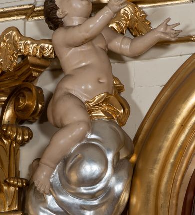Zdjęcie nr 19: Dwukondygnacyjny, jednoosiowy ołtarz ze zwieńczeniem uzyskał strukturę architektoniczną. Stipes ołtarzowy wykonano w formie granitowego prostopadłościanu z mensą. Na mensie na osi ołtarza ustawiono tabernakulum z tronem wystawienia. Tabernakulum otrzymało kształt drewnianej skrzynki obitej blachą z drzwiczkami w formie stojącego prostokąta, z sześcioma kwaterami przedstawiającymi sceny z Pisma Świętego. Całość zamknięto silnie wysuniętym gzymsem wypukłym od frontu. Tron wystawienia utworzono w formie baldachimu ozdobionego lambrekinem z chwostami. Ujmują go spływy wolutowe z podwieszoną tkaniną, dekorowane liśćmi akantu. W przestrzeni zaplecka tronu umieszczono w promienistej glorii medalion z chrystogramem "IHS". Nastawa została ustawiona na wysokim cokole, zwieńczonym profilowanym gzymsem z wyodrębnionymi dwoma wspornikami skierowanymi do wewnątrz. Retabulum ujmuje  zwrócona na zewnątrz opilastrowana para filarów, przed którymi stoi para kolumn o kapitelach kompozytowych dźwigających pełne belkowanie wyłamane na ich osi. W polu centralnym znajduje się nisza w kształcie stojącego prostokąta zwieńczonego przerwanym prostokątnie łukiem półkolistym, nadwieszonym. Niszę obramienia profilowana rama. W jej wnętrzu znajduje się obraz Wniebowzięcia Najświętsze Marii Panny w drewnianych sukienkach wotywnych. Druga kondygnacja ujęta została dwiema parami zwróconych na zewnątrz pilastrów o trzonach przechodzących w spływy wolutowe. Pilastry dźwigają gzyms wyłamany na ich osi, który w części centralnej przyjmuje kształt spłaszczonego łuku. W polu umieszczono obraz z przedstawieniem Michała Archanioła w formie stojącego prostokąta o wklęsłych, dłuższych krawędziach oraz krótszych o kształcie łuku półkolistego nadwieszonego. Nastawa zakończona została okiem Opatrzności Bożej w glorii promienistej. Na cokole przed podporami ustawiono cztery figury adorujących aniołów. Ramę w polu środkowym udekorowano ornamentem roślinnym. W górnych przyłuczach umieszczono figury puttów na obłokach. Fryz został ozdobiony kwiatowymi girlandami. Centralnie na osi na gzymsie zawieszono kartusz z monogramem Marii w polu. Na zewnętrznych krawędziach belkowania pierwszej kondygnacji siedzą dwie figury aniołów, a na spływach wolutowych cztery putta. W trzonach pilastrów drugiej kondygnacji widoczne są zwisy z ornamentem kwiatowym podwieszonym na wstążce. W polu centralnym na dole umieszczono dwa wieńce, a u góry dwie uskrzydlone główki anielskie. Na belkowaniu znajdują się dwa putta na obłokach. Struktura nastawy została polichromowana w kolorze kości słoniowej, natomiast kolumny, pilastry, profile i ornamentyka zostały wyzłocone, a obłoki posrebrzone.