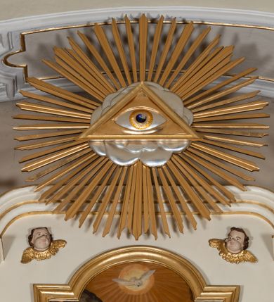 Zdjęcie nr 12: Dwukondygnacyjny, jednoosiowy ołtarz ze zwieńczeniem uzyskał strukturę architektoniczną. Stipes ołtarzowy wykonano w formie granitowego prostopadłościanu z mensą. Na mensie na osi ołtarza ustawiono tabernakulum z tronem wystawienia. Tabernakulum otrzymało kształt drewnianej skrzynki obitej blachą z drzwiczkami w formie stojącego prostokąta, z sześcioma kwaterami przedstawiającymi sceny z Pisma Świętego. Całość zamknięto silnie wysuniętym gzymsem wypukłym od frontu. Tron wystawienia utworzono w formie baldachimu ozdobionego lambrekinem z chwostami. Ujmują go spływy wolutowe z podwieszoną tkaniną, dekorowane liśćmi akantu. W przestrzeni zaplecka tronu umieszczono w promienistej glorii medalion z chrystogramem "IHS". Nastawa została ustawiona na wysokim cokole, zwieńczonym profilowanym gzymsem z wyodrębnionymi dwoma wspornikami skierowanymi do wewnątrz. Retabulum ujmuje  zwrócona na zewnątrz opilastrowana para filarów, przed którymi stoi para kolumn o kapitelach kompozytowych dźwigających pełne belkowanie wyłamane na ich osi. W polu centralnym znajduje się nisza w kształcie stojącego prostokąta zwieńczonego przerwanym prostokątnie łukiem półkolistym, nadwieszonym. Niszę obramienia profilowana rama. W jej wnętrzu znajduje się obraz Wniebowzięcia Najświętsze Marii Panny w drewnianych sukienkach wotywnych. Druga kondygnacja ujęta została dwiema parami zwróconych na zewnątrz pilastrów o trzonach przechodzących w spływy wolutowe. Pilastry dźwigają gzyms wyłamany na ich osi, który w części centralnej przyjmuje kształt spłaszczonego łuku. W polu umieszczono obraz z przedstawieniem Michała Archanioła w formie stojącego prostokąta o wklęsłych, dłuższych krawędziach oraz krótszych o kształcie łuku półkolistego nadwieszonego. Nastawa zakończona została okiem Opatrzności Bożej w glorii promienistej. Na cokole przed podporami ustawiono cztery figury adorujących aniołów. Ramę w polu środkowym udekorowano ornamentem roślinnym. W górnych przyłuczach umieszczono figury puttów na obłokach. Fryz został ozdobiony kwiatowymi girlandami. Centralnie na osi na gzymsie zawieszono kartusz z monogramem Marii w polu. Na zewnętrznych krawędziach belkowania pierwszej kondygnacji siedzą dwie figury aniołów, a na spływach wolutowych cztery putta. W trzonach pilastrów drugiej kondygnacji widoczne są zwisy z ornamentem kwiatowym podwieszonym na wstążce. W polu centralnym na dole umieszczono dwa wieńce, a u góry dwie uskrzydlone główki anielskie. Na belkowaniu znajdują się dwa putta na obłokach. Struktura nastawy została polichromowana w kolorze kości słoniowej, natomiast kolumny, pilastry, profile i ornamentyka zostały wyzłocone, a obłoki posrebrzone.