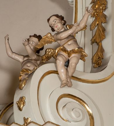 Zdjęcie nr 17: Dwukondygnacyjny, jednoosiowy ołtarz ze zwieńczeniem uzyskał strukturę architektoniczną. Stipes ołtarzowy wykonano w formie granitowego prostopadłościanu z mensą. Na mensie na osi ołtarza ustawiono tabernakulum z tronem wystawienia. Tabernakulum otrzymało kształt drewnianej skrzynki obitej blachą z drzwiczkami w formie stojącego prostokąta, z sześcioma kwaterami przedstawiającymi sceny z Pisma Świętego. Całość zamknięto silnie wysuniętym gzymsem wypukłym od frontu. Tron wystawienia utworzono w formie baldachimu ozdobionego lambrekinem z chwostami. Ujmują go spływy wolutowe z podwieszoną tkaniną, dekorowane liśćmi akantu. W przestrzeni zaplecka tronu umieszczono w promienistej glorii medalion z chrystogramem "IHS". Nastawa została ustawiona na wysokim cokole, zwieńczonym profilowanym gzymsem z wyodrębnionymi dwoma wspornikami skierowanymi do wewnątrz. Retabulum ujmuje  zwrócona na zewnątrz opilastrowana para filarów, przed którymi stoi para kolumn o kapitelach kompozytowych dźwigających pełne belkowanie wyłamane na ich osi. W polu centralnym znajduje się nisza w kształcie stojącego prostokąta zwieńczonego przerwanym prostokątnie łukiem półkolistym, nadwieszonym. Niszę obramienia profilowana rama. W jej wnętrzu znajduje się obraz Wniebowzięcia Najświętsze Marii Panny w drewnianych sukienkach wotywnych. Druga kondygnacja ujęta została dwiema parami zwróconych na zewnątrz pilastrów o trzonach przechodzących w spływy wolutowe. Pilastry dźwigają gzyms wyłamany na ich osi, który w części centralnej przyjmuje kształt spłaszczonego łuku. W polu umieszczono obraz z przedstawieniem Michała Archanioła w formie stojącego prostokąta o wklęsłych, dłuższych krawędziach oraz krótszych o kształcie łuku półkolistego nadwieszonego. Nastawa zakończona została okiem Opatrzności Bożej w glorii promienistej. Na cokole przed podporami ustawiono cztery figury adorujących aniołów. Ramę w polu środkowym udekorowano ornamentem roślinnym. W górnych przyłuczach umieszczono figury puttów na obłokach. Fryz został ozdobiony kwiatowymi girlandami. Centralnie na osi na gzymsie zawieszono kartusz z monogramem Marii w polu. Na zewnętrznych krawędziach belkowania pierwszej kondygnacji siedzą dwie figury aniołów, a na spływach wolutowych cztery putta. W trzonach pilastrów drugiej kondygnacji widoczne są zwisy z ornamentem kwiatowym podwieszonym na wstążce. W polu centralnym na dole umieszczono dwa wieńce, a u góry dwie uskrzydlone główki anielskie. Na belkowaniu znajdują się dwa putta na obłokach. Struktura nastawy została polichromowana w kolorze kości słoniowej, natomiast kolumny, pilastry, profile i ornamentyka zostały wyzłocone, a obłoki posrebrzone.