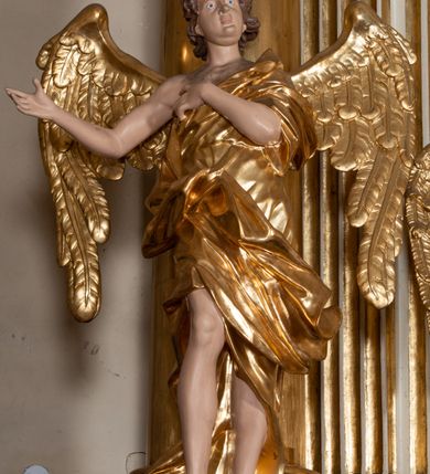 Zdjęcie nr 22: Dwukondygnacyjny, jednoosiowy ołtarz ze zwieńczeniem uzyskał strukturę architektoniczną. Stipes ołtarzowy wykonano w formie granitowego prostopadłościanu z mensą. Na mensie na osi ołtarza ustawiono tabernakulum z tronem wystawienia. Tabernakulum otrzymało kształt drewnianej skrzynki obitej blachą z drzwiczkami w formie stojącego prostokąta, z sześcioma kwaterami przedstawiającymi sceny z Pisma Świętego. Całość zamknięto silnie wysuniętym gzymsem wypukłym od frontu. Tron wystawienia utworzono w formie baldachimu ozdobionego lambrekinem z chwostami. Ujmują go spływy wolutowe z podwieszoną tkaniną, dekorowane liśćmi akantu. W przestrzeni zaplecka tronu umieszczono w promienistej glorii medalion z chrystogramem "IHS". Nastawa została ustawiona na wysokim cokole, zwieńczonym profilowanym gzymsem z wyodrębnionymi dwoma wspornikami skierowanymi do wewnątrz. Retabulum ujmuje  zwrócona na zewnątrz opilastrowana para filarów, przed którymi stoi para kolumn o kapitelach kompozytowych dźwigających pełne belkowanie wyłamane na ich osi. W polu centralnym znajduje się nisza w kształcie stojącego prostokąta zwieńczonego przerwanym prostokątnie łukiem półkolistym, nadwieszonym. Niszę obramienia profilowana rama. W jej wnętrzu znajduje się obraz Wniebowzięcia Najświętsze Marii Panny w drewnianych sukienkach wotywnych. Druga kondygnacja ujęta została dwiema parami zwróconych na zewnątrz pilastrów o trzonach przechodzących w spływy wolutowe. Pilastry dźwigają gzyms wyłamany na ich osi, który w części centralnej przyjmuje kształt spłaszczonego łuku. W polu umieszczono obraz z przedstawieniem Michała Archanioła w formie stojącego prostokąta o wklęsłych, dłuższych krawędziach oraz krótszych o kształcie łuku półkolistego nadwieszonego. Nastawa zakończona została okiem Opatrzności Bożej w glorii promienistej. Na cokole przed podporami ustawiono cztery figury adorujących aniołów. Ramę w polu środkowym udekorowano ornamentem roślinnym. W górnych przyłuczach umieszczono figury puttów na obłokach. Fryz został ozdobiony kwiatowymi girlandami. Centralnie na osi na gzymsie zawieszono kartusz z monogramem Marii w polu. Na zewnętrznych krawędziach belkowania pierwszej kondygnacji siedzą dwie figury aniołów, a na spływach wolutowych cztery putta. W trzonach pilastrów drugiej kondygnacji widoczne są zwisy z ornamentem kwiatowym podwieszonym na wstążce. W polu centralnym na dole umieszczono dwa wieńce, a u góry dwie uskrzydlone główki anielskie. Na belkowaniu znajdują się dwa putta na obłokach. Struktura nastawy została polichromowana w kolorze kości słoniowej, natomiast kolumny, pilastry, profile i ornamentyka zostały wyzłocone, a obłoki posrebrzone.