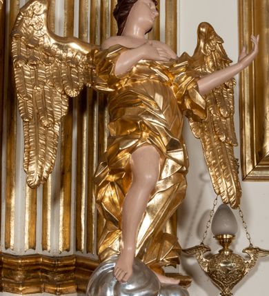 Zdjęcie nr 26: Dwukondygnacyjny, jednoosiowy ołtarz ze zwieńczeniem uzyskał strukturę architektoniczną. Stipes ołtarzowy wykonano w formie granitowego prostopadłościanu z mensą. Na mensie na osi ołtarza ustawiono tabernakulum z tronem wystawienia. Tabernakulum otrzymało kształt drewnianej skrzynki obitej blachą z drzwiczkami w formie stojącego prostokąta, z sześcioma kwaterami przedstawiającymi sceny z Pisma Świętego. Całość zamknięto silnie wysuniętym gzymsem wypukłym od frontu. Tron wystawienia utworzono w formie baldachimu ozdobionego lambrekinem z chwostami. Ujmują go spływy wolutowe z podwieszoną tkaniną, dekorowane liśćmi akantu. W przestrzeni zaplecka tronu umieszczono w promienistej glorii medalion z chrystogramem "IHS". Nastawa została ustawiona na wysokim cokole, zwieńczonym profilowanym gzymsem z wyodrębnionymi dwoma wspornikami skierowanymi do wewnątrz. Retabulum ujmuje  zwrócona na zewnątrz opilastrowana para filarów, przed którymi stoi para kolumn o kapitelach kompozytowych dźwigających pełne belkowanie wyłamane na ich osi. W polu centralnym znajduje się nisza w kształcie stojącego prostokąta zwieńczonego przerwanym prostokątnie łukiem półkolistym, nadwieszonym. Niszę obramienia profilowana rama. W jej wnętrzu znajduje się obraz Wniebowzięcia Najświętsze Marii Panny w drewnianych sukienkach wotywnych. Druga kondygnacja ujęta została dwiema parami zwróconych na zewnątrz pilastrów o trzonach przechodzących w spływy wolutowe. Pilastry dźwigają gzyms wyłamany na ich osi, który w części centralnej przyjmuje kształt spłaszczonego łuku. W polu umieszczono obraz z przedstawieniem Michała Archanioła w formie stojącego prostokąta o wklęsłych, dłuższych krawędziach oraz krótszych o kształcie łuku półkolistego nadwieszonego. Nastawa zakończona została okiem Opatrzności Bożej w glorii promienistej. Na cokole przed podporami ustawiono cztery figury adorujących aniołów. Ramę w polu środkowym udekorowano ornamentem roślinnym. W górnych przyłuczach umieszczono figury puttów na obłokach. Fryz został ozdobiony kwiatowymi girlandami. Centralnie na osi na gzymsie zawieszono kartusz z monogramem Marii w polu. Na zewnętrznych krawędziach belkowania pierwszej kondygnacji siedzą dwie figury aniołów, a na spływach wolutowych cztery putta. W trzonach pilastrów drugiej kondygnacji widoczne są zwisy z ornamentem kwiatowym podwieszonym na wstążce. W polu centralnym na dole umieszczono dwa wieńce, a u góry dwie uskrzydlone główki anielskie. Na belkowaniu znajdują się dwa putta na obłokach. Struktura nastawy została polichromowana w kolorze kości słoniowej, natomiast kolumny, pilastry, profile i ornamentyka zostały wyzłocone, a obłoki posrebrzone.