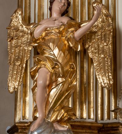 Zdjęcie nr 27: Dwukondygnacyjny, jednoosiowy ołtarz ze zwieńczeniem uzyskał strukturę architektoniczną. Stipes ołtarzowy wykonano w formie granitowego prostopadłościanu z mensą. Na mensie na osi ołtarza ustawiono tabernakulum z tronem wystawienia. Tabernakulum otrzymało kształt drewnianej skrzynki obitej blachą z drzwiczkami w formie stojącego prostokąta, z sześcioma kwaterami przedstawiającymi sceny z Pisma Świętego. Całość zamknięto silnie wysuniętym gzymsem wypukłym od frontu. Tron wystawienia utworzono w formie baldachimu ozdobionego lambrekinem z chwostami. Ujmują go spływy wolutowe z podwieszoną tkaniną, dekorowane liśćmi akantu. W przestrzeni zaplecka tronu umieszczono w promienistej glorii medalion z chrystogramem "IHS". Nastawa została ustawiona na wysokim cokole, zwieńczonym profilowanym gzymsem z wyodrębnionymi dwoma wspornikami skierowanymi do wewnątrz. Retabulum ujmuje  zwrócona na zewnątrz opilastrowana para filarów, przed którymi stoi para kolumn o kapitelach kompozytowych dźwigających pełne belkowanie wyłamane na ich osi. W polu centralnym znajduje się nisza w kształcie stojącego prostokąta zwieńczonego przerwanym prostokątnie łukiem półkolistym, nadwieszonym. Niszę obramienia profilowana rama. W jej wnętrzu znajduje się obraz Wniebowzięcia Najświętsze Marii Panny w drewnianych sukienkach wotywnych. Druga kondygnacja ujęta została dwiema parami zwróconych na zewnątrz pilastrów o trzonach przechodzących w spływy wolutowe. Pilastry dźwigają gzyms wyłamany na ich osi, który w części centralnej przyjmuje kształt spłaszczonego łuku. W polu umieszczono obraz z przedstawieniem Michała Archanioła w formie stojącego prostokąta o wklęsłych, dłuższych krawędziach oraz krótszych o kształcie łuku półkolistego nadwieszonego. Nastawa zakończona została okiem Opatrzności Bożej w glorii promienistej. Na cokole przed podporami ustawiono cztery figury adorujących aniołów. Ramę w polu środkowym udekorowano ornamentem roślinnym. W górnych przyłuczach umieszczono figury puttów na obłokach. Fryz został ozdobiony kwiatowymi girlandami. Centralnie na osi na gzymsie zawieszono kartusz z monogramem Marii w polu. Na zewnętrznych krawędziach belkowania pierwszej kondygnacji siedzą dwie figury aniołów, a na spływach wolutowych cztery putta. W trzonach pilastrów drugiej kondygnacji widoczne są zwisy z ornamentem kwiatowym podwieszonym na wstążce. W polu centralnym na dole umieszczono dwa wieńce, a u góry dwie uskrzydlone główki anielskie. Na belkowaniu znajdują się dwa putta na obłokach. Struktura nastawy została polichromowana w kolorze kości słoniowej, natomiast kolumny, pilastry, profile i ornamentyka zostały wyzłocone, a obłoki posrebrzone.