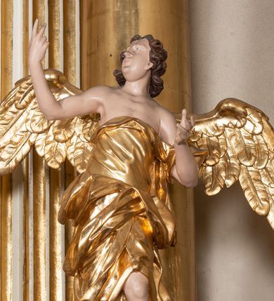 Zdjęcie nr 35: Dwukondygnacyjny, jednoosiowy ołtarz ze zwieńczeniem uzyskał strukturę architektoniczną. Stipes ołtarzowy wykonano w formie granitowego prostopadłościanu z mensą. Na mensie na osi ołtarza ustawiono tabernakulum z tronem wystawienia. Tabernakulum otrzymało kształt drewnianej skrzynki obitej blachą z drzwiczkami w formie stojącego prostokąta, z sześcioma kwaterami przedstawiającymi sceny z Pisma Świętego. Całość zamknięto silnie wysuniętym gzymsem wypukłym od frontu. Tron wystawienia utworzono w formie baldachimu ozdobionego lambrekinem z chwostami. Ujmują go spływy wolutowe z podwieszoną tkaniną, dekorowane liśćmi akantu. W przestrzeni zaplecka tronu umieszczono w promienistej glorii medalion z chrystogramem "IHS". Nastawa została ustawiona na wysokim cokole, zwieńczonym profilowanym gzymsem z wyodrębnionymi dwoma wspornikami skierowanymi do wewnątrz. Retabulum ujmuje  zwrócona na zewnątrz opilastrowana para filarów, przed którymi stoi para kolumn o kapitelach kompozytowych dźwigających pełne belkowanie wyłamane na ich osi. W polu centralnym znajduje się nisza w kształcie stojącego prostokąta zwieńczonego przerwanym prostokątnie łukiem półkolistym, nadwieszonym. Niszę obramienia profilowana rama. W jej wnętrzu znajduje się obraz Wniebowzięcia Najświętsze Marii Panny w drewnianych sukienkach wotywnych. Druga kondygnacja ujęta została dwiema parami zwróconych na zewnątrz pilastrów o trzonach przechodzących w spływy wolutowe. Pilastry dźwigają gzyms wyłamany na ich osi, który w części centralnej przyjmuje kształt spłaszczonego łuku. W polu umieszczono obraz z przedstawieniem Michała Archanioła w formie stojącego prostokąta o wklęsłych, dłuższych krawędziach oraz krótszych o kształcie łuku półkolistego nadwieszonego. Nastawa zakończona została okiem Opatrzności Bożej w glorii promienistej. Na cokole przed podporami ustawiono cztery figury adorujących aniołów. Ramę w polu środkowym udekorowano ornamentem roślinnym. W górnych przyłuczach umieszczono figury puttów na obłokach. Fryz został ozdobiony kwiatowymi girlandami. Centralnie na osi na gzymsie zawieszono kartusz z monogramem Marii w polu. Na zewnętrznych krawędziach belkowania pierwszej kondygnacji siedzą dwie figury aniołów, a na spływach wolutowych cztery putta. W trzonach pilastrów drugiej kondygnacji widoczne są zwisy z ornamentem kwiatowym podwieszonym na wstążce. W polu centralnym na dole umieszczono dwa wieńce, a u góry dwie uskrzydlone główki anielskie. Na belkowaniu znajdują się dwa putta na obłokach. Struktura nastawy została polichromowana w kolorze kości słoniowej, natomiast kolumny, pilastry, profile i ornamentyka zostały wyzłocone, a obłoki posrebrzone.