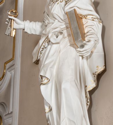 Zdjęcie nr 42: Dwukondygnacyjny, jednoosiowy ołtarz ze zwieńczeniem uzyskał strukturę architektoniczną. Stipes ołtarzowy wykonano w formie granitowego prostopadłościanu z mensą. Na mensie na osi ołtarza ustawiono tabernakulum z tronem wystawienia. Tabernakulum otrzymało kształt drewnianej skrzynki obitej blachą z drzwiczkami w formie stojącego prostokąta, z sześcioma kwaterami przedstawiającymi sceny z Pisma Świętego. Całość zamknięto silnie wysuniętym gzymsem wypukłym od frontu. Tron wystawienia utworzono w formie baldachimu ozdobionego lambrekinem z chwostami. Ujmują go spływy wolutowe z podwieszoną tkaniną, dekorowane liśćmi akantu. W przestrzeni zaplecka tronu umieszczono w promienistej glorii medalion z chrystogramem &quot;IHS&quot;. Nastawa została ustawiona na wysokim cokole, zwieńczonym profilowanym gzymsem z wyodrębnionymi dwoma wspornikami skierowanymi do wewnątrz. Retabulum ujmuje  zwrócona na zewnątrz opilastrowana para filarów, przed którymi stoi para kolumn o kapitelach kompozytowych dźwigających pełne belkowanie wyłamane na ich osi. W polu centralnym znajduje się nisza w kształcie stojącego prostokąta zwieńczonego przerwanym prostokątnie łukiem półkolistym, nadwieszonym. Niszę obramienia profilowana rama. W jej wnętrzu znajduje się obraz Wniebowzięcia Najświętsze Marii Panny w drewnianych sukienkach wotywnych. Druga kondygnacja ujęta została dwiema parami zwróconych na zewnątrz pilastrów o trzonach przechodzących w spływy wolutowe. Pilastry dźwigają gzyms wyłamany na ich osi, który w części centralnej przyjmuje kształt spłaszczonego łuku. W polu umieszczono obraz z przedstawieniem Michała Archanioła w formie stojącego prostokąta o wklęsłych, dłuższych krawędziach oraz krótszych o kształcie łuku półkolistego nadwieszonego. Nastawa zakończona została okiem Opatrzności Bożej w glorii promienistej. Na cokole przed podporami ustawiono cztery figury adorujących aniołów. Ramę w polu środkowym udekorowano ornamentem roślinnym. W górnych przyłuczach umieszczono figury puttów na obłokach. Fryz został ozdobiony kwiatowymi girlandami. Centralnie na osi na gzymsie zawieszono kartusz z monogramem Marii w polu. Na zewnętrznych krawędziach belkowania pierwszej kondygnacji siedzą dwie figury aniołów, a na spływach wolutowych cztery putta. W trzonach pilastrów drugiej kondygnacji widoczne są zwisy z ornamentem kwiatowym podwieszonym na wstążce. W polu centralnym na dole umieszczono dwa wieńce, a u góry dwie uskrzydlone główki anielskie. Na belkowaniu znajdują się dwa putta na obłokach. Struktura nastawy została polichromowana w kolorze kości słoniowej, natomiast kolumny, pilastry, profile i ornamentyka zostały wyzłocone, a obłoki posrebrzone.