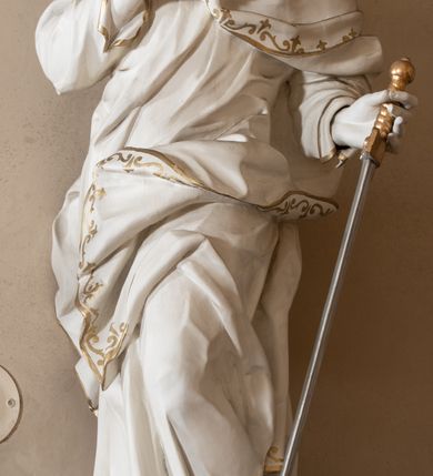 Zdjęcie nr 46: Dwukondygnacyjny, jednoosiowy ołtarz ze zwieńczeniem uzyskał strukturę architektoniczną. Stipes ołtarzowy wykonano w formie granitowego prostopadłościanu z mensą. Na mensie na osi ołtarza ustawiono tabernakulum z tronem wystawienia. Tabernakulum otrzymało kształt drewnianej skrzynki obitej blachą z drzwiczkami w formie stojącego prostokąta, z sześcioma kwaterami przedstawiającymi sceny z Pisma Świętego. Całość zamknięto silnie wysuniętym gzymsem wypukłym od frontu. Tron wystawienia utworzono w formie baldachimu ozdobionego lambrekinem z chwostami. Ujmują go spływy wolutowe z podwieszoną tkaniną, dekorowane liśćmi akantu. W przestrzeni zaplecka tronu umieszczono w promienistej glorii medalion z chrystogramem &quot;IHS&quot;. Nastawa została ustawiona na wysokim cokole, zwieńczonym profilowanym gzymsem z wyodrębnionymi dwoma wspornikami skierowanymi do wewnątrz. Retabulum ujmuje  zwrócona na zewnątrz opilastrowana para filarów, przed którymi stoi para kolumn o kapitelach kompozytowych dźwigających pełne belkowanie wyłamane na ich osi. W polu centralnym znajduje się nisza w kształcie stojącego prostokąta zwieńczonego przerwanym prostokątnie łukiem półkolistym, nadwieszonym. Niszę obramienia profilowana rama. W jej wnętrzu znajduje się obraz Wniebowzięcia Najświętsze Marii Panny w drewnianych sukienkach wotywnych. Druga kondygnacja ujęta została dwiema parami zwróconych na zewnątrz pilastrów o trzonach przechodzących w spływy wolutowe. Pilastry dźwigają gzyms wyłamany na ich osi, który w części centralnej przyjmuje kształt spłaszczonego łuku. W polu umieszczono obraz z przedstawieniem Michała Archanioła w formie stojącego prostokąta o wklęsłych, dłuższych krawędziach oraz krótszych o kształcie łuku półkolistego nadwieszonego. Nastawa zakończona została okiem Opatrzności Bożej w glorii promienistej. Na cokole przed podporami ustawiono cztery figury adorujących aniołów. Ramę w polu środkowym udekorowano ornamentem roślinnym. W górnych przyłuczach umieszczono figury puttów na obłokach. Fryz został ozdobiony kwiatowymi girlandami. Centralnie na osi na gzymsie zawieszono kartusz z monogramem Marii w polu. Na zewnętrznych krawędziach belkowania pierwszej kondygnacji siedzą dwie figury aniołów, a na spływach wolutowych cztery putta. W trzonach pilastrów drugiej kondygnacji widoczne są zwisy z ornamentem kwiatowym podwieszonym na wstążce. W polu centralnym na dole umieszczono dwa wieńce, a u góry dwie uskrzydlone główki anielskie. Na belkowaniu znajdują się dwa putta na obłokach. Struktura nastawy została polichromowana w kolorze kości słoniowej, natomiast kolumny, pilastry, profile i ornamentyka zostały wyzłocone, a obłoki posrebrzone.