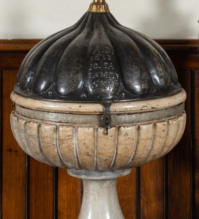 Zdjęcie nr 1: Marmurowa chrzcielnica uzyskała kształt kielicha. Na sześciennym cokole ustawiono czworoboczny postument, z którego wyrasta gruszkowa tralka podtrzymująca, spłaszczoną, sferyczną czarę dekorowaną imitacją płaskiego puklowania z wywiniętym brzegiem. Blaszana pokrywa uzyskała formę trybowanej półkuli, zakończonej aplikowaną kulą z krzyżem z gołębicą Ducha Świętego. Na pokrywie znajduje się trybowana inskrypcja: „A[NNO] D[OMINI] / 1613 /10.SA/LA MIEY/SKY".