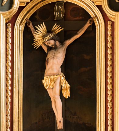 Zdjęcie nr 2: Nastawa ołtarza Ukrzyżowania uzyskała formę architektonicznego retabulum dwukondygnacyjnego, jednoosiowego ze zwieńczeniem w postaci promienistej glorii. Drewniany stipes ołtarzowy uzyskał formę prostopadłościanu podtrzymującego drewnianą mensę z marmurowym portatylem. Na mensie na osi ustawiono architektoniczne tabernakulum w formie drewnianej skrzynki na cokole, na planie trapezu o wypukłej ściance przedniej i wklęsłych ramionach. Ścianka przednia ujęta została parą zdwojonych pilastrów podtrzymujących imposty, których trzon przyjmuje formę wolut. Na ściance przedniej usytuowana została nisza obrotowa w formie stojącego prostokąta zamkniętego łukiem półkolistym nadwieszonym z uskokiem w karbowanej ramie. Widoczne pilastry dźwigają pełne belkowanie, zaś nad polem głównym wyłącznie gzyms. Drzwiczki tabernakulum ozdobiono płaskorzeźbionym przedstawieniem baranka leżącego na księdze o siedmiu pieczęciach w glorii promienistej. Retabulum ustawiono na trójstrefowym cokole. W dwóch pierwszych strefach znalazły się dwie pary wyodrębnionych prostopadłościanów stanowiących cokoły dla kolumn. Nastawę flankują dwie pary kolumn o kapitelach korynckich, spośród których wewnętrza ma skręcone trzony, a zewnętrzna kanelowane. Kolumny dźwigają pełne belkowanie wyłamane na ich osi, pod kątem, zaś nad polem środkowym wyłącznie gzyms. Niemal w całości pole główne wypełnia wnęka w formie stojącego prostokąta zamkniętego łukiem odcinkowym, nadwieszonym z uskokiem, ujęta profilowaną ramą. Wewnątrz widoczna jest mniejsza w formie stojącego prostokąta zamkniętego łukiem odcinkowym z figurą Chrystusa Ukrzyżowanego. Druga kondygnacja ustawiona jest także na cokole. Flankują ją dwie pary kolumn o kapitelach korynckich, spośród których wewnętrza ma skręcone trzony, zewnętrzna kanelowane. Kolumny dźwigają pełne belkowanie wyłamane na ich osi, pod kątem oraz fragmenty półkolistego przyczółka. W polu umieszczono obraz Zwiastowania w formie stojącego prostokąta zamkniętego trójbocznie, ujętego ramą zdobioną wolim okiem. Całość zakończona szczytem ujętym wolutami z medalionem z monogramem "IHS" w otoku z obłoków w glorii promienistej. Cokół dolny zdobiony został płycinami i rozetami. Pomiędzy kolumnami usytuowano zwisy kwiatowe na wstędze. Uszy ołtarza utworzone zostały z akantu. Fryzy występujące w retabulum dekorowany są złoconymi rozetami, zaś przyłucza ozdobiono ornamentem roślinnym. Drugą kondygnację flankują uszy utworzone z akantu i wstęgi. Na belkowaniu umieszczono siedzące figury aniołów, a na drugiej kondygnacji putta i wazony. Struktura ołtarza została polichromowana w kolorze szaro-zielonym z elementami szaro-brązowymi ze złoconymi profilami, ramami i ornamentyką, natomiast kręcone trzony posrebrzono.