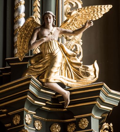 Zdjęcie nr 5: Nastawa ołtarza Ukrzyżowania uzyskała formę architektonicznego retabulum dwukondygnacyjnego, jednoosiowego ze zwieńczeniem w postaci promienistej glorii. Drewniany stipes ołtarzowy uzyskał formę prostopadłościanu podtrzymującego drewnianą mensę z marmurowym portatylem. Na mensie na osi ustawiono architektoniczne tabernakulum w formie drewnianej skrzynki na cokole, na planie trapezu o wypukłej ściance przedniej i wklęsłych ramionach. Ścianka przednia ujęta została parą zdwojonych pilastrów podtrzymujących imposty, których trzon przyjmuje formę wolut. Na ściance przedniej usytuowana została nisza obrotowa w formie stojącego prostokąta zamkniętego łukiem półkolistym nadwieszonym z uskokiem w karbowanej ramie. Widoczne pilastry dźwigają pełne belkowanie, zaś nad polem głównym wyłącznie gzyms. Drzwiczki tabernakulum ozdobiono płaskorzeźbionym przedstawieniem baranka leżącego na księdze o siedmiu pieczęciach w glorii promienistej. Retabulum ustawiono na trójstrefowym cokole. W dwóch pierwszych strefach znalazły się dwie pary wyodrębnionych prostopadłościanów stanowiących cokoły dla kolumn. Nastawę flankują dwie pary kolumn o kapitelach korynckich, spośród których wewnętrza ma skręcone trzony, a zewnętrzna kanelowane. Kolumny dźwigają pełne belkowanie wyłamane na ich osi, pod kątem, zaś nad polem środkowym wyłącznie gzyms. Niemal w całości pole główne wypełnia wnęka w formie stojącego prostokąta zamkniętego łukiem odcinkowym, nadwieszonym z uskokiem, ujęta profilowaną ramą. Wewnątrz widoczna jest mniejsza w formie stojącego prostokąta zamkniętego łukiem odcinkowym z figurą Chrystusa Ukrzyżowanego. Druga kondygnacja ustawiona jest także na cokole. Flankują ją dwie pary kolumn o kapitelach korynckich, spośród których wewnętrza ma skręcone trzony, zewnętrzna kanelowane. Kolumny dźwigają pełne belkowanie wyłamane na ich osi, pod kątem oraz fragmenty półkolistego przyczółka. W polu umieszczono obraz Zwiastowania w formie stojącego prostokąta zamkniętego trójbocznie, ujętego ramą zdobioną wolim okiem. Całość zakończona szczytem ujętym wolutami z medalionem z monogramem "IHS" w otoku z obłoków w glorii promienistej. Cokół dolny zdobiony został płycinami i rozetami. Pomiędzy kolumnami usytuowano zwisy kwiatowe na wstędze. Uszy ołtarza utworzone zostały z akantu. Fryzy występujące w retabulum dekorowany są złoconymi rozetami, zaś przyłucza ozdobiono ornamentem roślinnym. Drugą kondygnację flankują uszy utworzone z akantu i wstęgi. Na belkowaniu umieszczono siedzące figury aniołów, a na drugiej kondygnacji putta i wazony. Struktura ołtarza została polichromowana w kolorze szaro-zielonym z elementami szaro-brązowymi ze złoconymi profilami, ramami i ornamentyką, natomiast kręcone trzony posrebrzono.