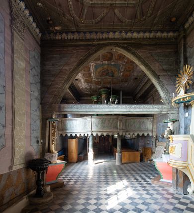 Zdjęcie nr 2: Architektoniczny prospekt organowy uzyskał pięcioosiowe założenie jednokondygnacyjne ustawione na wysokim cokole. Osie pierwsza, trzecia i piąta z większymi piszczałkami są wypukłe. Pierwsza i piąta są niższe od trzeciej. Wszystkie zwieńczone zostały pełnym belkowaniem z wydatnym, profilowanym gzymsem. W osi środkowej dodatkowo znalazł się ażurowy, złocony lambrekin oraz ornament ze złoconej wici roślinnej. Osie parzyste są niższe z płaskimi, prostokątnymi niszami mieszczącymi mniejsze piszczałki. Wieńczą je profilowano-fazowane konsole. Struktura prospektu została polichromowana w odcieniach morskiej zieleni, zaś ornamentyka i załamania profili architektonicznych wyzłocono.