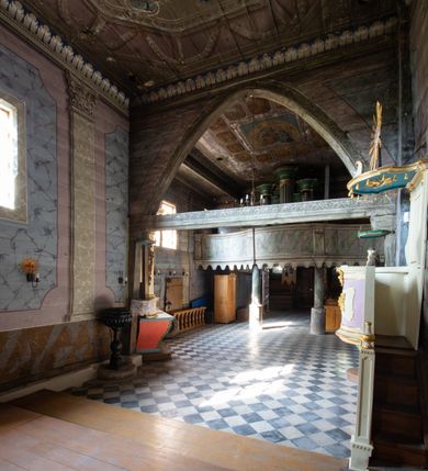 Zdjęcie nr 3: Architektoniczny prospekt organowy uzyskał pięcioosiowe założenie jednokondygnacyjne ustawione na wysokim cokole. Osie pierwsza, trzecia i piąta z większymi piszczałkami są wypukłe. Pierwsza i piąta są niższe od trzeciej. Wszystkie zwieńczone zostały pełnym belkowaniem z wydatnym, profilowanym gzymsem. W osi środkowej dodatkowo znalazł się ażurowy, złocony lambrekin oraz ornament ze złoconej wici roślinnej. Osie parzyste są niższe z płaskimi, prostokątnymi niszami mieszczącymi mniejsze piszczałki. Wieńczą je profilowano-fazowane konsole. Struktura prospektu została polichromowana w odcieniach morskiej zieleni, zaś ornamentyka i załamania profili architektonicznych wyzłocono.