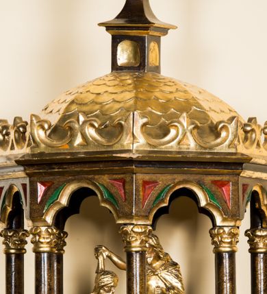 Zdjęcie nr 2: Kielichowa chrzcielnica ustawiona został na prostopadłościennej podstawie, o trzonie na rzucie koła w typie wazonowatym zakończonym pierścieniem. Czara przyjęła kształt kolisty, spłaszczony i puklowany z pierścieniem przy górnej krawędzi. Pokrywę wykonano na rzucie koła zwieńczonego rozbudowaną ażurową strukturą w kształcie kapliczki. Jej cokół wykonano na rzucie koła przechodzącego w ośmioboczny postument, poniżej którego znalazła się dekoracja z motywem trójkątnych liści spływających ku dołowi. Na postumencie ustawiono cokoliki z kolumienkami o kapitelach korynckich, podtrzymujące profilowane belkowanie zamykające przestrzeń między nimi łukiem trójlistnym. W podniebieniu zwieńczenia wyobrażono gołębicę Ducha Świętego, a na jego zwieńczeniu usytuowano spłaszczona kopułę krytą złoconą łuską z latarnią z kwiatonem. Wewnątrz struktury na ośmiobocznym podwyższeniu znalazła się rzeźbiona grupa przedstawiająca chrzest Chrystusa. Jezus ukazany został w pozycji klęczącej z rękami skrzyżowanymi na piersiach, o nagim torsie, okryty luźną szatą. Stojący obok św. Jan Chrzciciel prawą ręką uniesioną nad głową Chrystusa przechyla naczynie z wodą. Ubrany jest w wielbłądzią skórę. Ornamenty i dekoracja architektoniczna przykrywy zostały pozłocone. 