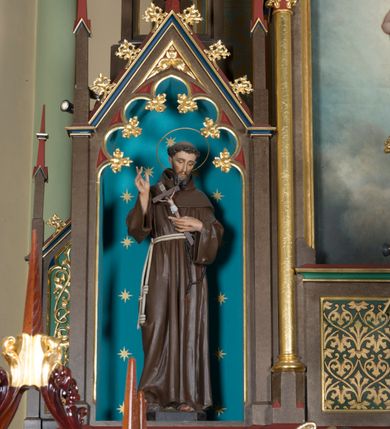 Zdjęcie nr 12: Wolnostojący, jednokondygnacyjny, trójosiowy ołtarz uzyskał formę architektoniczną ze zwieńczeniem. Stipes ołtarzowy przyjął formę leżącego prostopadłościanu ustawionego na podeście z dwoma gradusami, na którym wsparto drewnianą mensę z portatylem. Fronton stipesu podzielono za pomocą trzech płyciny, czworoboczną na osi, a w osiach skrajnych prostokątnymi. W płycinie pola środkowego umieszczono płaskorzeźbiony krzyż równoramienny wpisany w okręg. Natomiast w polach bocznych znalazły się ostrołukowe arkadki wypełnione malowanym i złoconym ornamentem roślinno-kwiatowym. Na mensie na osi ustawiono architektoniczne tabernakulum z tronem eucharystycznym. Jego dwuskrzydłowe drzwi ujęte zostały parą lizen, których płyciny wypełniono płaskorzeźbionym ornamentem. Drzwiczki ozdobiono płaskorzeźbioną dekoracją z winną latoroślą i srebrnymi literami „A” i „Ω”. Na lizenach wsparto niewielki, fazowany gzyms. Ponad nim usytuowano tron eucharystyczny w formie aediculi flankowanej złoconymi kolumnami na postumentach z liściastymi kapitelami podtrzymującymi imposty przechodzące w pinakle z kwiatonami. Pomiędzy nimi znalazła się wimperga z czołganiami i wieńczącym ją pinaklem z kwiatonem. Wimpergę wypełnia stylizowany łuk trójlistny. W niszy na tylnej ściance wykonano malarską dekorację z przedstawionym kielichem z jaśniejącym nad nim Najświętszym Sercem Pana Jezusa w koronie cierniowej, na tle dekoracji roślinnej. Całoś baldachimu nakrywa daszek siodłowy. Tabernakulum flankują dwa adorujące anioły w jasnych szatach ustawione na profilowanych postumentach dekorowanych na licu łacińskimi napisami "Adoremus" i "Venite". Nastawa ołtarzowa ustawiona została na wysokim, dwustrefowym cokole. Górną strefę artykułowano za pomocą czworobocznych, zielonych płycin wypełnionych płaskorzeźbionym i złoconym ornamentem roślinnym, obramienionych profilowanymi listwami. Cokół zwieńczony został profilowanym gzymsem. Część środkowa nastawy jest wyższa i szersza od osi bocznych. Tworzy ją pole w kształcie stojącego prostokąta zamknięte u góry łukiem siodłowym, ujętego złoconą, profilowaną ramą. Pole flankują dwie smukłe kolumienki z liściastymi kapitelami, ustawione na postumentach, przechodzące w pinakle zwieńczone kwiatonami. Pomiędzy pinaklami usytuowano wimpergę wypełnioną maswerkiem z czterolistnym polem, w którym znajduje się napis:"S[anc]t[us] Mrtinus". Wimpergę zakończoną pinaklem z kwiatonem zdobią czołgani. Ponad nią wypiętrzone zostało ażurowe zwieńczenie utworzone z podwójnych ostrołukowych arkadek flankujących fialę z kwiatonem. W polu kondygnacji prezentowany jest obraz ze św. Marcinem oraz dwa pozostałe na zasuwie z przedstawienie Madonny Sykstyńskiej oraz Matki Boskiej Nieustającej Pomocy. Poniżej pola obrazowego wprowadzono płycinę w kształcie leżącego prostokąta, dekorowaną malowaną, złoconą ornamentyką na zielonym tle. W osiach bocznych znalazły się dwie aedicule zwieńczone wimpergami z czołgankami i kwiatonem, flankowane parą wysmuklonych pinakli z kwiatonami. Górną część aediculi wypełnia arkatura. W niszach na niebieskim tle ze złotymi gwiazdami ustawiono figury św. Franciszka z Asyżu i św. Elżbiety z Turyngii. Kondygnację flankują ażurowe struktury utworzone z płycin ujętych smukłymi pinaklami, wypełnionymi płaskorzeźbionym ornamentem roślinnym. Struktura ołtarza polichromowana została w odcieniach zgaszonego brązu. Załamania profili architektonicznych pomalowano na czerwono, zielono i niebiesko, natomiast ornamenty wyzłocono. 