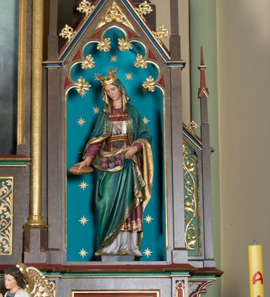 Zdjęcie nr 10: Wolnostojący, jednokondygnacyjny, trójosiowy ołtarz uzyskał formę architektoniczną ze zwieńczeniem. Stipes ołtarzowy przyjął formę leżącego prostopadłościanu ustawionego na podeście z dwoma gradusami, na którym wsparto drewnianą mensę z portatylem. Fronton stipesu podzielono za pomocą trzech płyciny, czworoboczną na osi, a w osiach skrajnych prostokątnymi. W płycinie pola środkowego umieszczono płaskorzeźbiony krzyż równoramienny wpisany w okręg. Natomiast w polach bocznych znalazły się ostrołukowe arkadki wypełnione malowanym i złoconym ornamentem roślinno-kwiatowym. Na mensie na osi ustawiono architektoniczne tabernakulum z tronem eucharystycznym. Jego dwuskrzydłowe drzwi ujęte zostały parą lizen, których płyciny wypełniono płaskorzeźbionym ornamentem. Drzwiczki ozdobiono płaskorzeźbioną dekoracją z winną latoroślą i srebrnymi literami „A” i „Ω”. Na lizenach wsparto niewielki, fazowany gzyms. Ponad nim usytuowano tron eucharystyczny w formie aediculi flankowanej złoconymi kolumnami na postumentach z liściastymi kapitelami podtrzymującymi imposty przechodzące w pinakle z kwiatonami. Pomiędzy nimi znalazła się wimperga z czołganiami i wieńczącym ją pinaklem z kwiatonem. Wimpergę wypełnia stylizowany łuk trójlistny. W niszy na tylnej ściance wykonano malarską dekorację z przedstawionym kielichem z jaśniejącym nad nim Najświętszym Sercem Pana Jezusa w koronie cierniowej, na tle dekoracji roślinnej. Całoś baldachimu nakrywa daszek siodłowy. Tabernakulum flankują dwa adorujące anioły w jasnych szatach ustawione na profilowanych postumentach dekorowanych na licu łacińskimi napisami "Adoremus" i "Venite". Nastawa ołtarzowa ustawiona została na wysokim, dwustrefowym cokole. Górną strefę artykułowano za pomocą czworobocznych, zielonych płycin wypełnionych płaskorzeźbionym i złoconym ornamentem roślinnym, obramienionych profilowanymi listwami. Cokół zwieńczony został profilowanym gzymsem. Część środkowa nastawy jest wyższa i szersza od osi bocznych. Tworzy ją pole w kształcie stojącego prostokąta zamknięte u góry łukiem siodłowym, ujętego złoconą, profilowaną ramą. Pole flankują dwie smukłe kolumienki z liściastymi kapitelami, ustawione na postumentach, przechodzące w pinakle zwieńczone kwiatonami. Pomiędzy pinaklami usytuowano wimpergę wypełnioną maswerkiem z czterolistnym polem, w którym znajduje się napis:"S[anc]t[us] Mrtinus". Wimpergę zakończoną pinaklem z kwiatonem zdobią czołgani. Ponad nią wypiętrzone zostało ażurowe zwieńczenie utworzone z podwójnych ostrołukowych arkadek flankujących fialę z kwiatonem. W polu kondygnacji prezentowany jest obraz ze św. Marcinem oraz dwa pozostałe na zasuwie z przedstawienie Madonny Sykstyńskiej oraz Matki Boskiej Nieustającej Pomocy. Poniżej pola obrazowego wprowadzono płycinę w kształcie leżącego prostokąta, dekorowaną malowaną, złoconą ornamentyką na zielonym tle. W osiach bocznych znalazły się dwie aedicule zwieńczone wimpergami z czołgankami i kwiatonem, flankowane parą wysmuklonych pinakli z kwiatonami. Górną część aediculi wypełnia arkatura. W niszach na niebieskim tle ze złotymi gwiazdami ustawiono figury św. Franciszka z Asyżu i św. Elżbiety z Turyngii. Kondygnację flankują ażurowe struktury utworzone z płycin ujętych smukłymi pinaklami, wypełnionymi płaskorzeźbionym ornamentem roślinnym. Struktura ołtarza polichromowana została w odcieniach zgaszonego brązu. Załamania profili architektonicznych pomalowano na czerwono, zielono i niebiesko, natomiast ornamenty wyzłocono. 