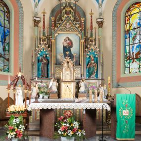 Zdjęcie nr 1: Wolnostojący, jednokondygnacyjny, trójosiowy ołtarz uzyskał formę architektoniczną ze zwieńczeniem. Stipes ołtarzowy przyjął formę leżącego prostopadłościanu ustawionego na podeście z dwoma gradusami, na którym wsparto drewnianą mensę z portatylem. Fronton stipesu podzielono za pomocą trzech płyciny, czworoboczną na osi, a w osiach skrajnych prostokątnymi. W płycinie pola środkowego umieszczono płaskorzeźbiony krzyż równoramienny wpisany w okręg. Natomiast w polach bocznych znalazły się ostrołukowe arkadki wypełnione malowanym i złoconym ornamentem roślinno-kwiatowym. Na mensie na osi ustawiono architektoniczne tabernakulum z tronem eucharystycznym. Jego dwuskrzydłowe drzwi ujęte zostały parą lizen, których płyciny wypełniono płaskorzeźbionym ornamentem. Drzwiczki ozdobiono płaskorzeźbioną dekoracją z winną latoroślą i srebrnymi literami „A” i „Ω”. Na lizenach wsparto niewielki, fazowany gzyms. Ponad nim usytuowano tron eucharystyczny w formie aediculi flankowanej złoconymi kolumnami na postumentach z liściastymi kapitelami podtrzymującymi imposty przechodzące w pinakle z kwiatonami. Pomiędzy nimi znalazła się wimperga z czołganiami i wieńczącym ją pinaklem z kwiatonem. Wimpergę wypełnia stylizowany łuk trójlistny. W niszy na tylnej ściance wykonano malarską dekorację z przedstawionym kielichem z jaśniejącym nad nim Najświętszym Sercem Pana Jezusa w koronie cierniowej, na tle dekoracji roślinnej. Całoś baldachimu nakrywa daszek siodłowy. Tabernakulum flankują dwa adorujące anioły w jasnych szatach ustawione na profilowanych postumentach dekorowanych na licu łacińskimi napisami "Adoremus" i "Venite". Nastawa ołtarzowa ustawiona została na wysokim, dwustrefowym cokole. Górną strefę artykułowano za pomocą czworobocznych, zielonych płycin wypełnionych płaskorzeźbionym i złoconym ornamentem roślinnym, obramienionych profilowanymi listwami. Cokół zwieńczony został profilowanym gzymsem. Część środkowa nastawy jest wyższa i szersza od osi bocznych. Tworzy ją pole w kształcie stojącego prostokąta zamknięte u góry łukiem siodłowym, ujętego złoconą, profilowaną ramą. Pole flankują dwie smukłe kolumienki z liściastymi kapitelami, ustawione na postumentach, przechodzące w pinakle zwieńczone kwiatonami. Pomiędzy pinaklami usytuowano wimpergę wypełnioną maswerkiem z czterolistnym polem, w którym znajduje się napis:"S[anc]t[us] Mrtinus". Wimpergę zakończoną pinaklem z kwiatonem zdobią czołgani. Ponad nią wypiętrzone zostało ażurowe zwieńczenie utworzone z podwójnych ostrołukowych arkadek flankujących fialę z kwiatonem. W polu kondygnacji prezentowany jest obraz ze św. Marcinem oraz dwa pozostałe na zasuwie z przedstawienie Madonny Sykstyńskiej oraz Matki Boskiej Nieustającej Pomocy. Poniżej pola obrazowego wprowadzono płycinę w kształcie leżącego prostokąta, dekorowaną malowaną, złoconą ornamentyką na zielonym tle. W osiach bocznych znalazły się dwie aedicule zwieńczone wimpergami z czołgankami i kwiatonem, flankowane parą wysmuklonych pinakli z kwiatonami. Górną część aediculi wypełnia arkatura. W niszach na niebieskim tle ze złotymi gwiazdami ustawiono figury św. Franciszka z Asyżu i św. Elżbiety z Turyngii. Kondygnację flankują ażurowe struktury utworzone z płycin ujętych smukłymi pinaklami, wypełnionymi płaskorzeźbionym ornamentem roślinnym. Struktura ołtarza polichromowana została w odcieniach zgaszonego brązu. Załamania profili architektonicznych pomalowano na czerwono, zielono i niebiesko, natomiast ornamenty wyzłocono. 