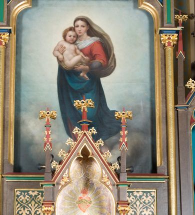 Zdjęcie nr 8: Wolnostojący, jednokondygnacyjny, trójosiowy ołtarz uzyskał formę architektoniczną ze zwieńczeniem. Stipes ołtarzowy przyjął formę leżącego prostopadłościanu ustawionego na podeście z dwoma gradusami, na którym wsparto drewnianą mensę z portatylem. Fronton stipesu podzielono za pomocą trzech płyciny, czworoboczną na osi, a w osiach skrajnych prostokątnymi. W płycinie pola środkowego umieszczono płaskorzeźbiony krzyż równoramienny wpisany w okręg. Natomiast w polach bocznych znalazły się ostrołukowe arkadki wypełnione malowanym i złoconym ornamentem roślinno-kwiatowym. Na mensie na osi ustawiono architektoniczne tabernakulum z tronem eucharystycznym. Jego dwuskrzydłowe drzwi ujęte zostały parą lizen, których płyciny wypełniono płaskorzeźbionym ornamentem. Drzwiczki ozdobiono płaskorzeźbioną dekoracją z winną latoroślą i srebrnymi literami „A” i „Ω”. Na lizenach wsparto niewielki, fazowany gzyms. Ponad nim usytuowano tron eucharystyczny w formie aediculi flankowanej złoconymi kolumnami na postumentach z liściastymi kapitelami podtrzymującymi imposty przechodzące w pinakle z kwiatonami. Pomiędzy nimi znalazła się wimperga z czołganiami i wieńczącym ją pinaklem z kwiatonem. Wimpergę wypełnia stylizowany łuk trójlistny. W niszy na tylnej ściance wykonano malarską dekorację z przedstawionym kielichem z jaśniejącym nad nim Najświętszym Sercem Pana Jezusa w koronie cierniowej, na tle dekoracji roślinnej. Całoś baldachimu nakrywa daszek siodłowy. Tabernakulum flankują dwa adorujące anioły w jasnych szatach ustawione na profilowanych postumentach dekorowanych na licu łacińskimi napisami "Adoremus" i "Venite". Nastawa ołtarzowa ustawiona została na wysokim, dwustrefowym cokole. Górną strefę artykułowano za pomocą czworobocznych, zielonych płycin wypełnionych płaskorzeźbionym i złoconym ornamentem roślinnym, obramienionych profilowanymi listwami. Cokół zwieńczony został profilowanym gzymsem. Część środkowa nastawy jest wyższa i szersza od osi bocznych. Tworzy ją pole w kształcie stojącego prostokąta zamknięte u góry łukiem siodłowym, ujętego złoconą, profilowaną ramą. Pole flankują dwie smukłe kolumienki z liściastymi kapitelami, ustawione na postumentach, przechodzące w pinakle zwieńczone kwiatonami. Pomiędzy pinaklami usytuowano wimpergę wypełnioną maswerkiem z czterolistnym polem, w którym znajduje się napis:"S[anc]t[us] Mrtinus". Wimpergę zakończoną pinaklem z kwiatonem zdobią czołgani. Ponad nią wypiętrzone zostało ażurowe zwieńczenie utworzone z podwójnych ostrołukowych arkadek flankujących fialę z kwiatonem. W polu kondygnacji prezentowany jest obraz ze św. Marcinem oraz dwa pozostałe na zasuwie z przedstawienie Madonny Sykstyńskiej oraz Matki Boskiej Nieustającej Pomocy. Poniżej pola obrazowego wprowadzono płycinę w kształcie leżącego prostokąta, dekorowaną malowaną, złoconą ornamentyką na zielonym tle. W osiach bocznych znalazły się dwie aedicule zwieńczone wimpergami z czołgankami i kwiatonem, flankowane parą wysmuklonych pinakli z kwiatonami. Górną część aediculi wypełnia arkatura. W niszach na niebieskim tle ze złotymi gwiazdami ustawiono figury św. Franciszka z Asyżu i św. Elżbiety z Turyngii. Kondygnację flankują ażurowe struktury utworzone z płycin ujętych smukłymi pinaklami, wypełnionymi płaskorzeźbionym ornamentem roślinnym. Struktura ołtarza polichromowana została w odcieniach zgaszonego brązu. Załamania profili architektonicznych pomalowano na czerwono, zielono i niebiesko, natomiast ornamenty wyzłocono. 