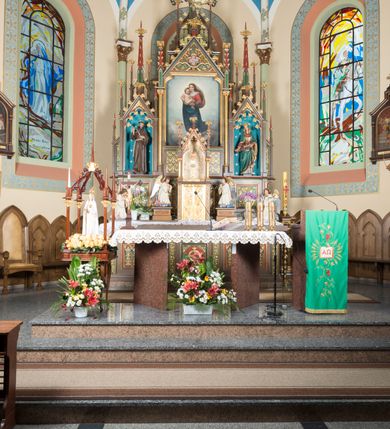 Zdjęcie nr 2: Wolnostojący, jednokondygnacyjny, trójosiowy ołtarz uzyskał formę architektoniczną ze zwieńczeniem. Stipes ołtarzowy przyjął formę leżącego prostopadłościanu ustawionego na podeście z dwoma gradusami, na którym wsparto drewnianą mensę z portatylem. Fronton stipesu podzielono za pomocą trzech płyciny, czworoboczną na osi, a w osiach skrajnych prostokątnymi. W płycinie pola środkowego umieszczono płaskorzeźbiony krzyż równoramienny wpisany w okręg. Natomiast w polach bocznych znalazły się ostrołukowe arkadki wypełnione malowanym i złoconym ornamentem roślinno-kwiatowym. Na mensie na osi ustawiono architektoniczne tabernakulum z tronem eucharystycznym. Jego dwuskrzydłowe drzwi ujęte zostały parą lizen, których płyciny wypełniono płaskorzeźbionym ornamentem. Drzwiczki ozdobiono płaskorzeźbioną dekoracją z winną latoroślą i srebrnymi literami „A” i „Ω”. Na lizenach wsparto niewielki, fazowany gzyms. Ponad nim usytuowano tron eucharystyczny w formie aediculi flankowanej złoconymi kolumnami na postumentach z liściastymi kapitelami podtrzymującymi imposty przechodzące w pinakle z kwiatonami. Pomiędzy nimi znalazła się wimperga z czołganiami i wieńczącym ją pinaklem z kwiatonem. Wimpergę wypełnia stylizowany łuk trójlistny. W niszy na tylnej ściance wykonano malarską dekorację z przedstawionym kielichem z jaśniejącym nad nim Najświętszym Sercem Pana Jezusa w koronie cierniowej, na tle dekoracji roślinnej. Całoś baldachimu nakrywa daszek siodłowy. Tabernakulum flankują dwa adorujące anioły w jasnych szatach ustawione na profilowanych postumentach dekorowanych na licu łacińskimi napisami "Adoremus" i "Venite". Nastawa ołtarzowa ustawiona została na wysokim, dwustrefowym cokole. Górną strefę artykułowano za pomocą czworobocznych, zielonych płycin wypełnionych płaskorzeźbionym i złoconym ornamentem roślinnym, obramienionych profilowanymi listwami. Cokół zwieńczony został profilowanym gzymsem. Część środkowa nastawy jest wyższa i szersza od osi bocznych. Tworzy ją pole w kształcie stojącego prostokąta zamknięte u góry łukiem siodłowym, ujętego złoconą, profilowaną ramą. Pole flankują dwie smukłe kolumienki z liściastymi kapitelami, ustawione na postumentach, przechodzące w pinakle zwieńczone kwiatonami. Pomiędzy pinaklami usytuowano wimpergę wypełnioną maswerkiem z czterolistnym polem, w którym znajduje się napis:"S[anc]t[us] Mrtinus". Wimpergę zakończoną pinaklem z kwiatonem zdobią czołgani. Ponad nią wypiętrzone zostało ażurowe zwieńczenie utworzone z podwójnych ostrołukowych arkadek flankujących fialę z kwiatonem. W polu kondygnacji prezentowany jest obraz ze św. Marcinem oraz dwa pozostałe na zasuwie z przedstawienie Madonny Sykstyńskiej oraz Matki Boskiej Nieustającej Pomocy. Poniżej pola obrazowego wprowadzono płycinę w kształcie leżącego prostokąta, dekorowaną malowaną, złoconą ornamentyką na zielonym tle. W osiach bocznych znalazły się dwie aedicule zwieńczone wimpergami z czołgankami i kwiatonem, flankowane parą wysmuklonych pinakli z kwiatonami. Górną część aediculi wypełnia arkatura. W niszach na niebieskim tle ze złotymi gwiazdami ustawiono figury św. Franciszka z Asyżu i św. Elżbiety z Turyngii. Kondygnację flankują ażurowe struktury utworzone z płycin ujętych smukłymi pinaklami, wypełnionymi płaskorzeźbionym ornamentem roślinnym. Struktura ołtarza polichromowana została w odcieniach zgaszonego brązu. Załamania profili architektonicznych pomalowano na czerwono, zielono i niebiesko, natomiast ornamenty wyzłocono. 